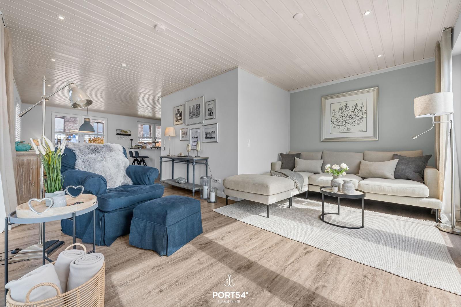 Wohnzimmer mit Sofa, Sessel und Holzboden. Decke mit Holzverkleidung.
