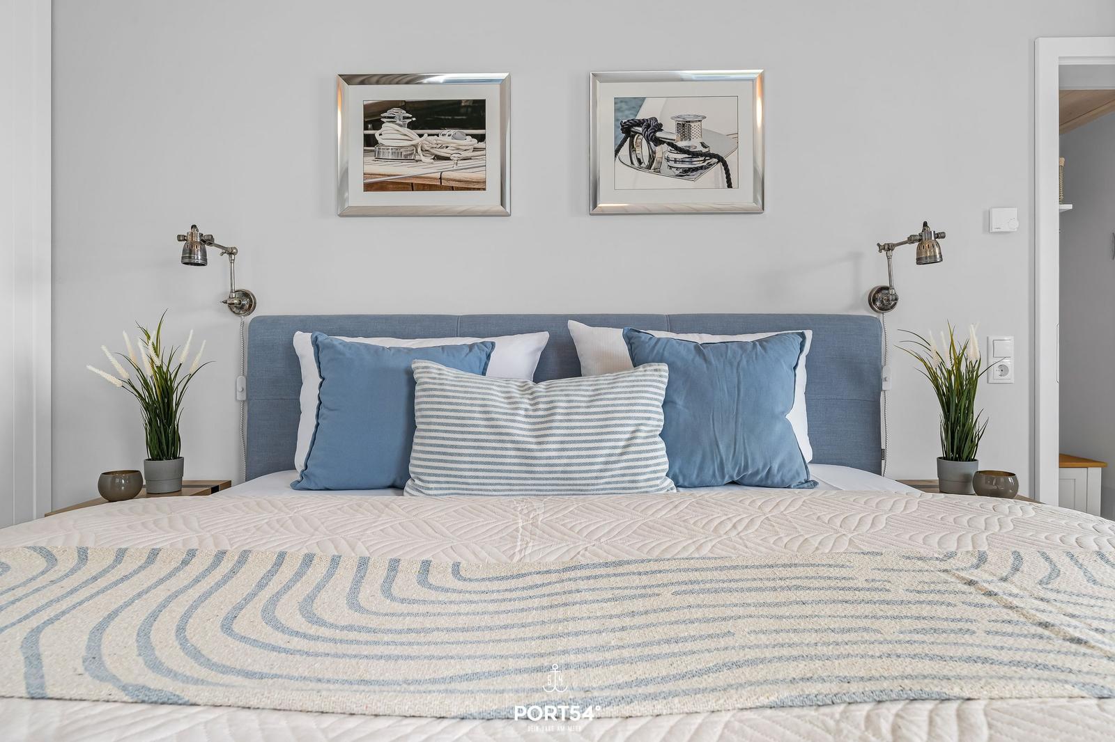 Schlafzimmer mit blauem Bett, Kissen und Wandbildern