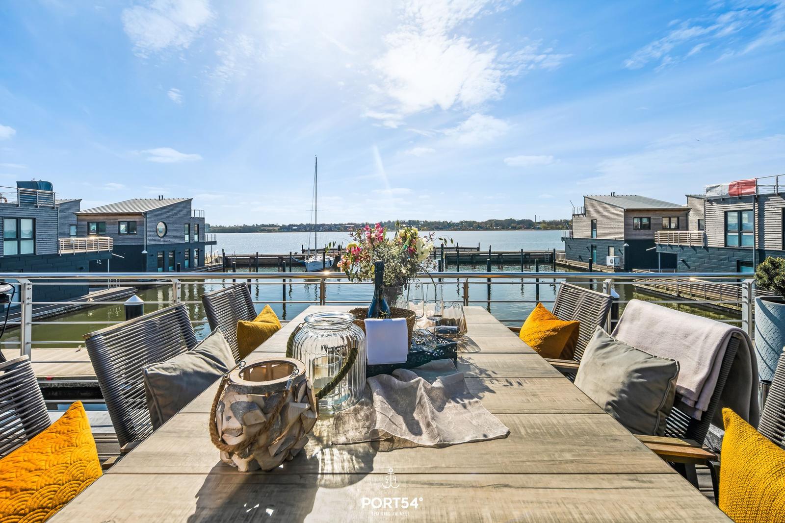 Terrasse mit Tisch und Stühlen, Blick auf Wasser und Häuser