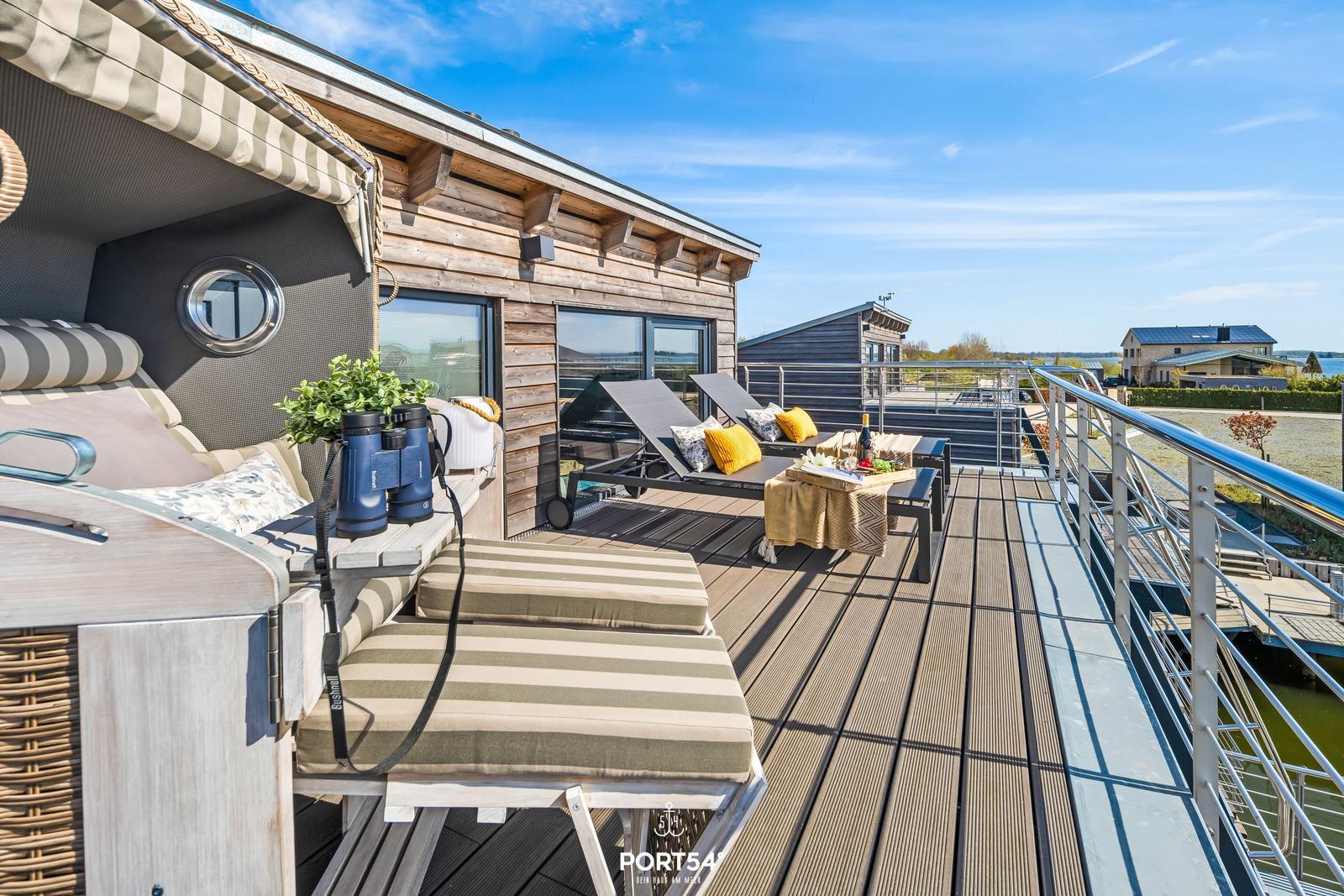 Terrasse mit Liegen, Tisch und Blick auf Wasser und Häuser