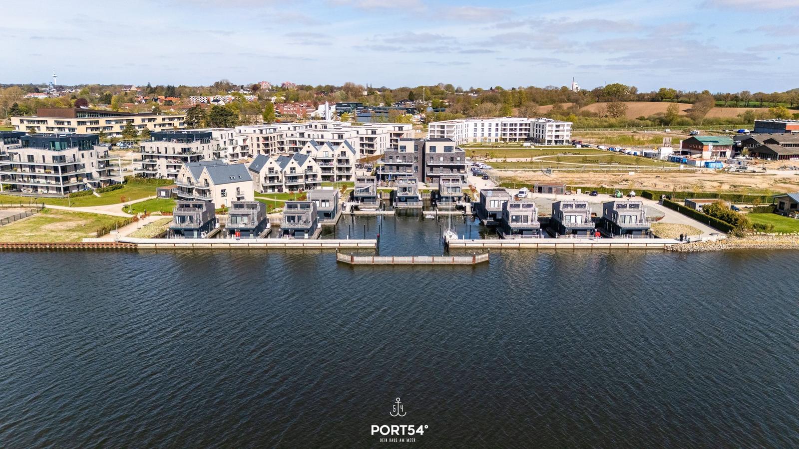 Modernes Wohngebiet am Wasser mit Bootsanlegern und Grünflächen.