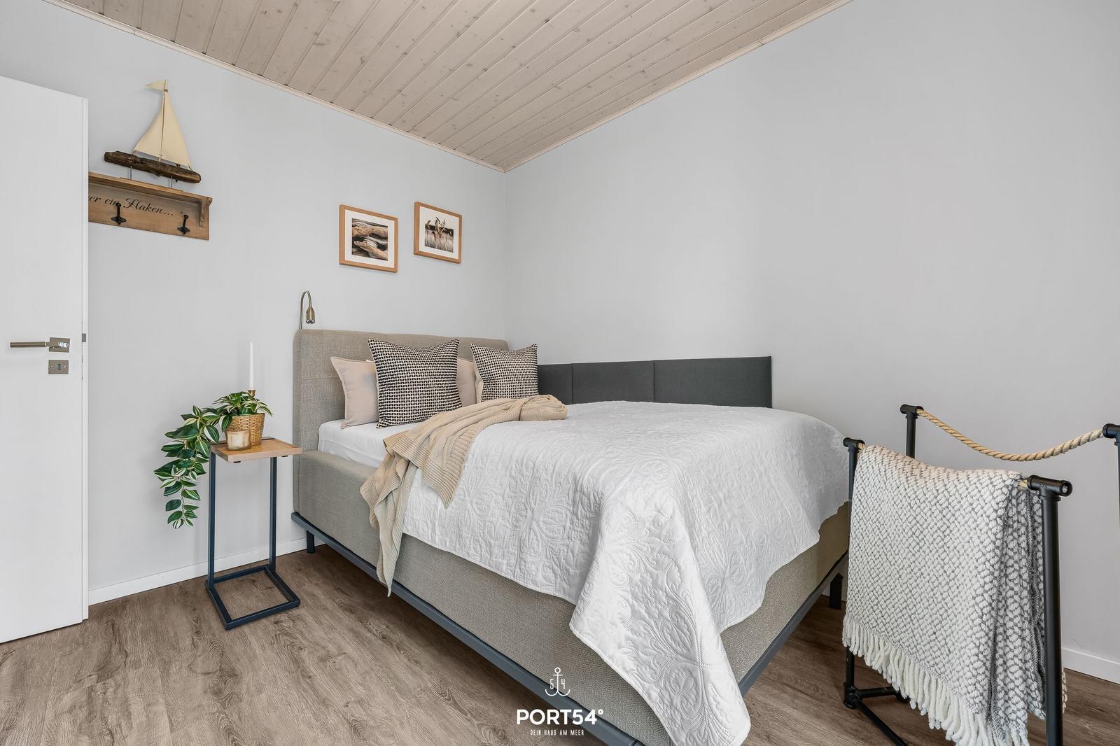 Schlafzimmer mit Bett, Nachttisch und Wanddekoration.