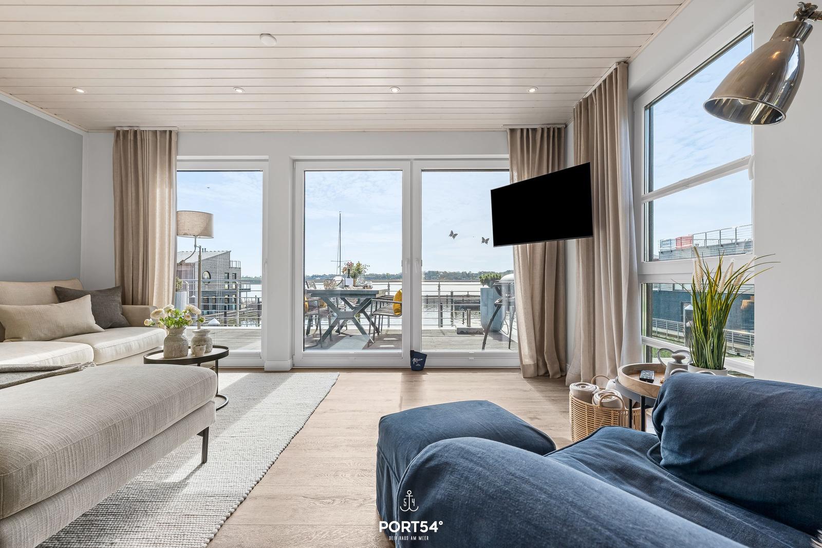 Wohnraum mit Blick auf Hafen, Sofa, Fernseher und Terrasse.