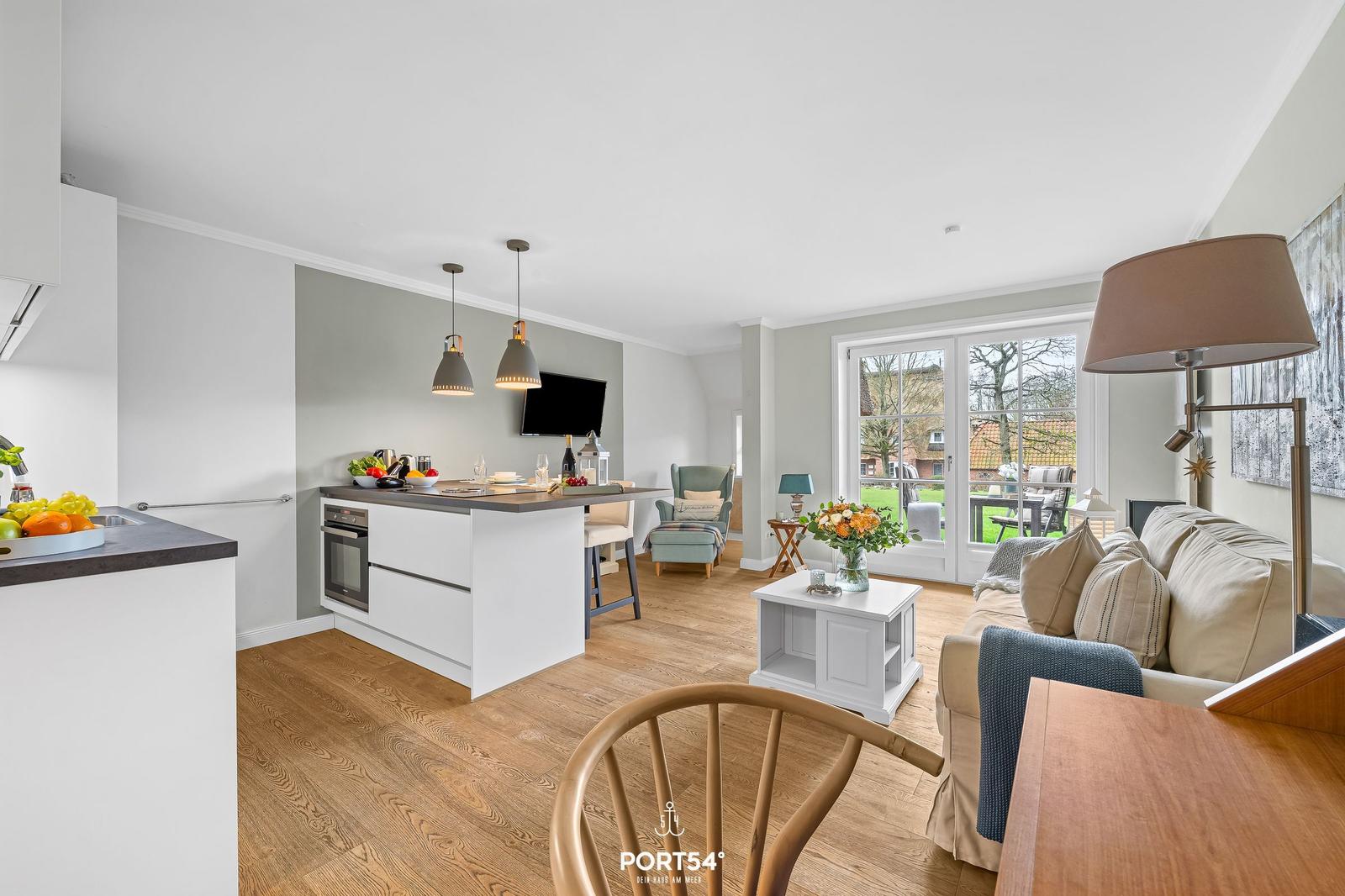 Küche mit Essbereich und Wohnzimmer mit Sofa und Glastüren.