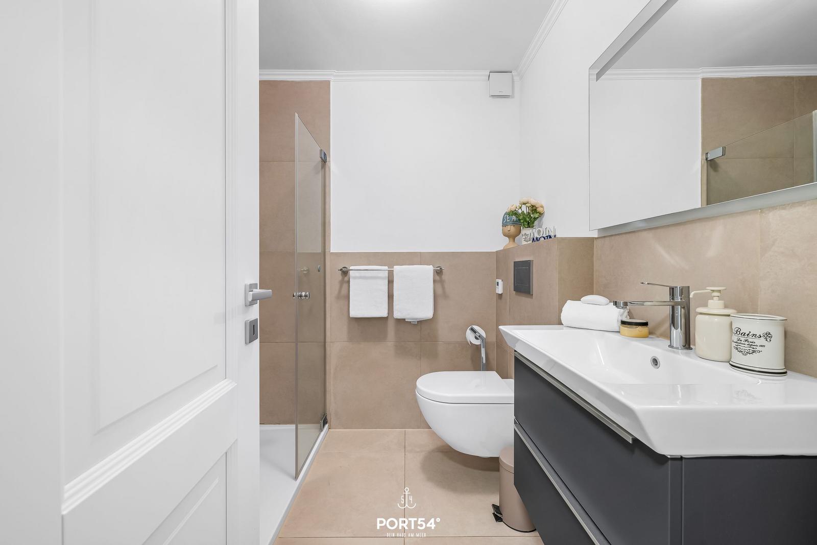 Badezimmer mit Dusche, Toilette und Waschbecken mit Spiegelschrank.