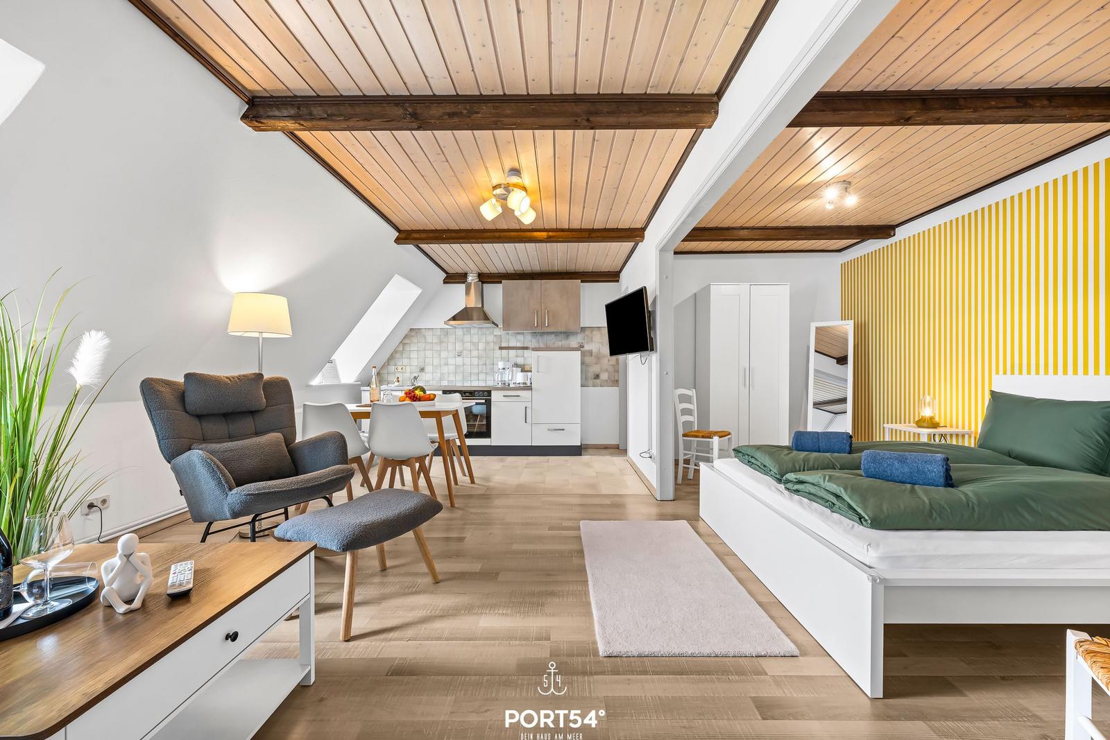 Wohnbereich mit Schlafzimmer, Küche und Holzdecke. Bett mit grünen Laken.