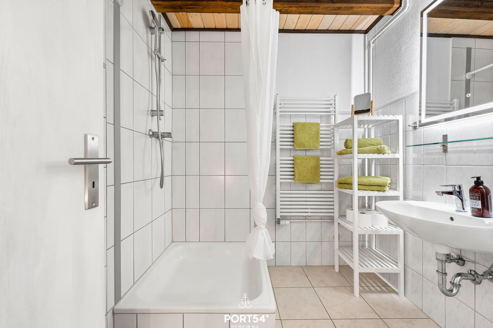 Badezimmer mit Badewanne, Dusche, Waschbecken und Handtüchern.