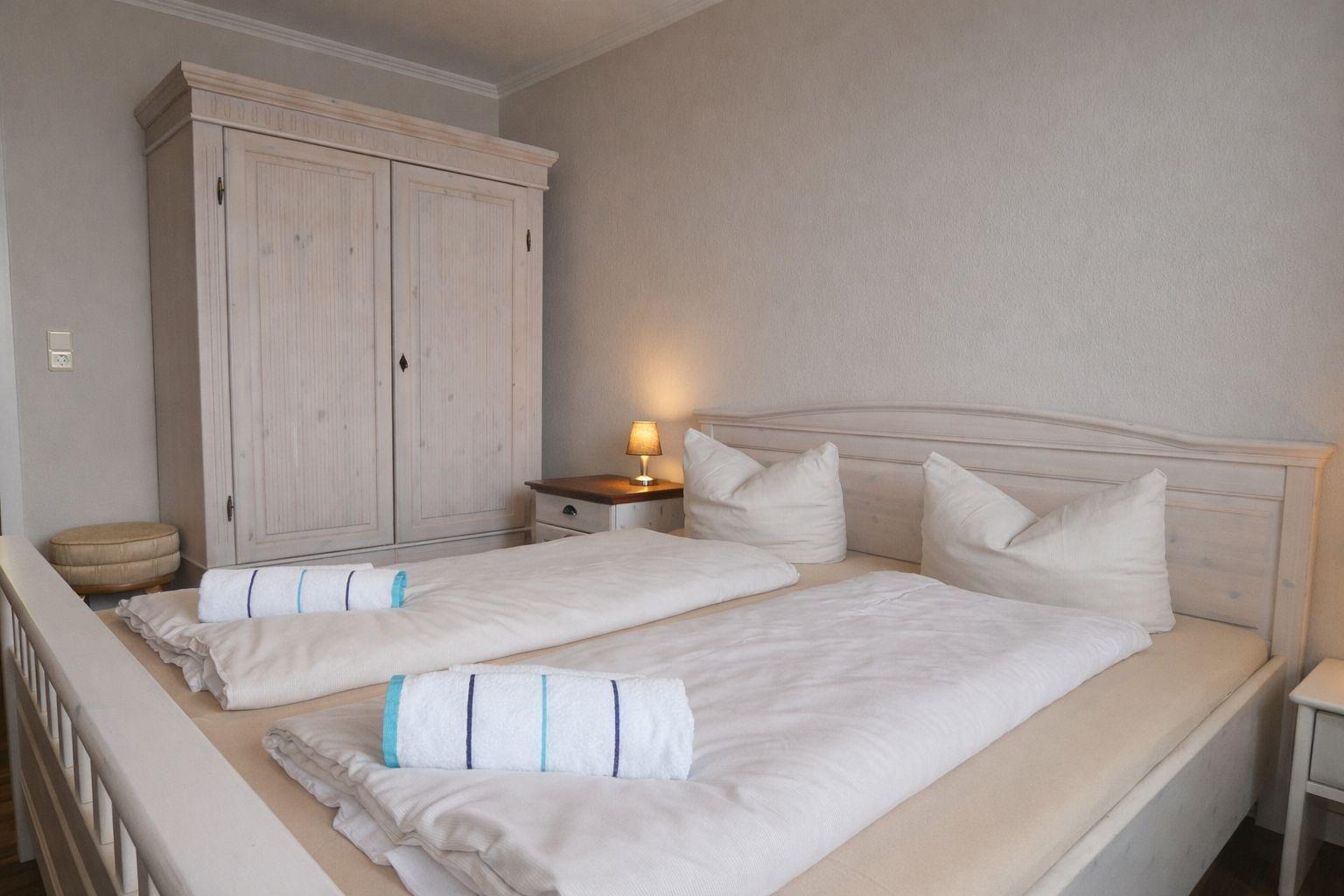 Ein Schlafzimmer mit Doppelbett, Kleiderschrank und Nachttisch mit Lampe.