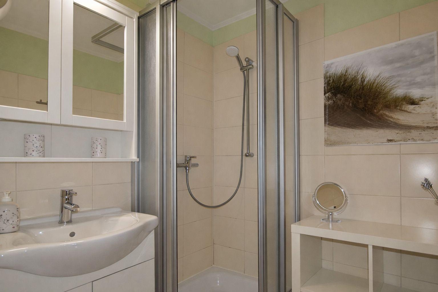 Badezimmer mit Dusche, Waschbecken und Spiegelschrank.