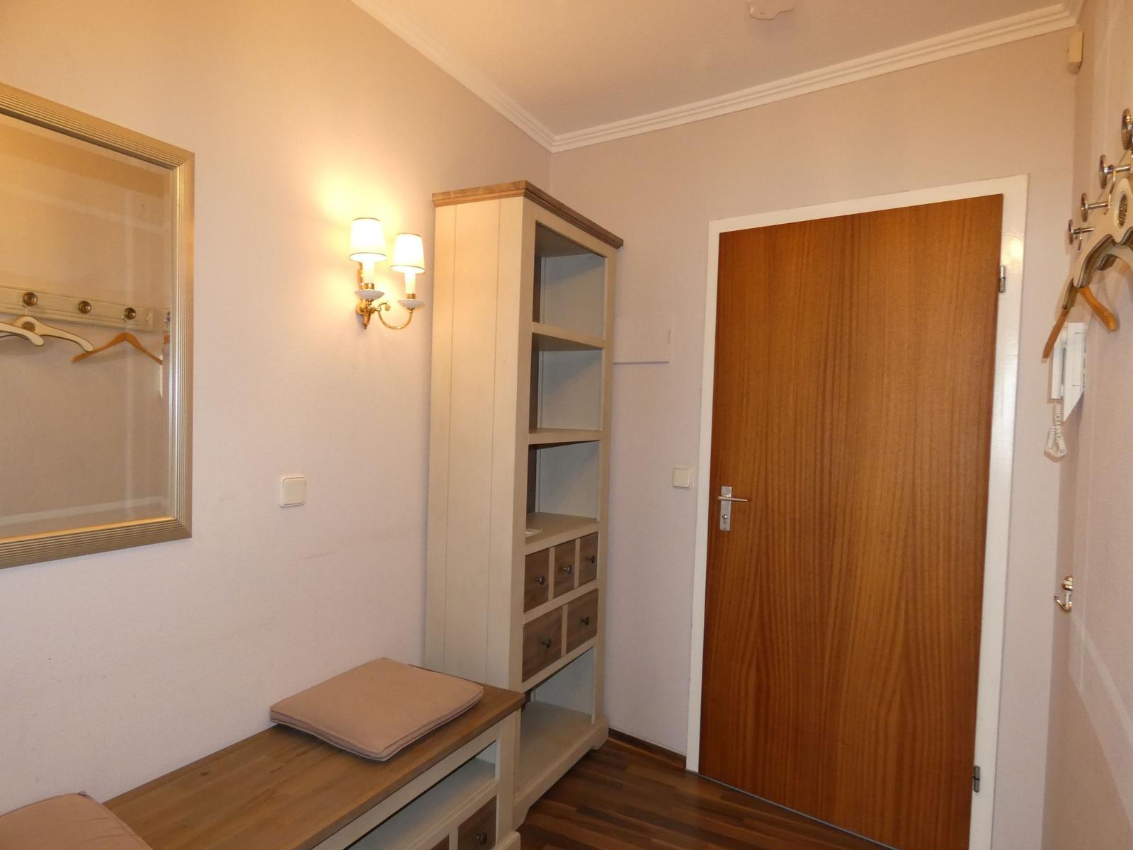 Eingangsbereich mit Spiegelschrank, Holztür und Wandbeleuchtung.