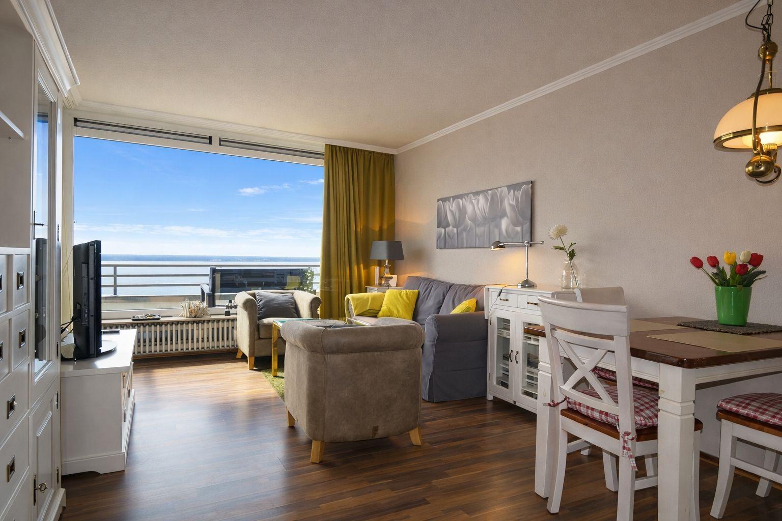Wohnzimmer mit Essbereich und Meerblick durch große Fenster.