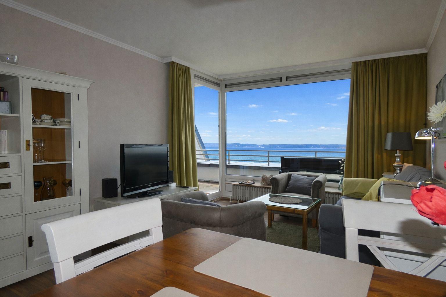 Wohnzimmer mit Blick auf Meer, Sofa, Couchtisch und Essbereich.