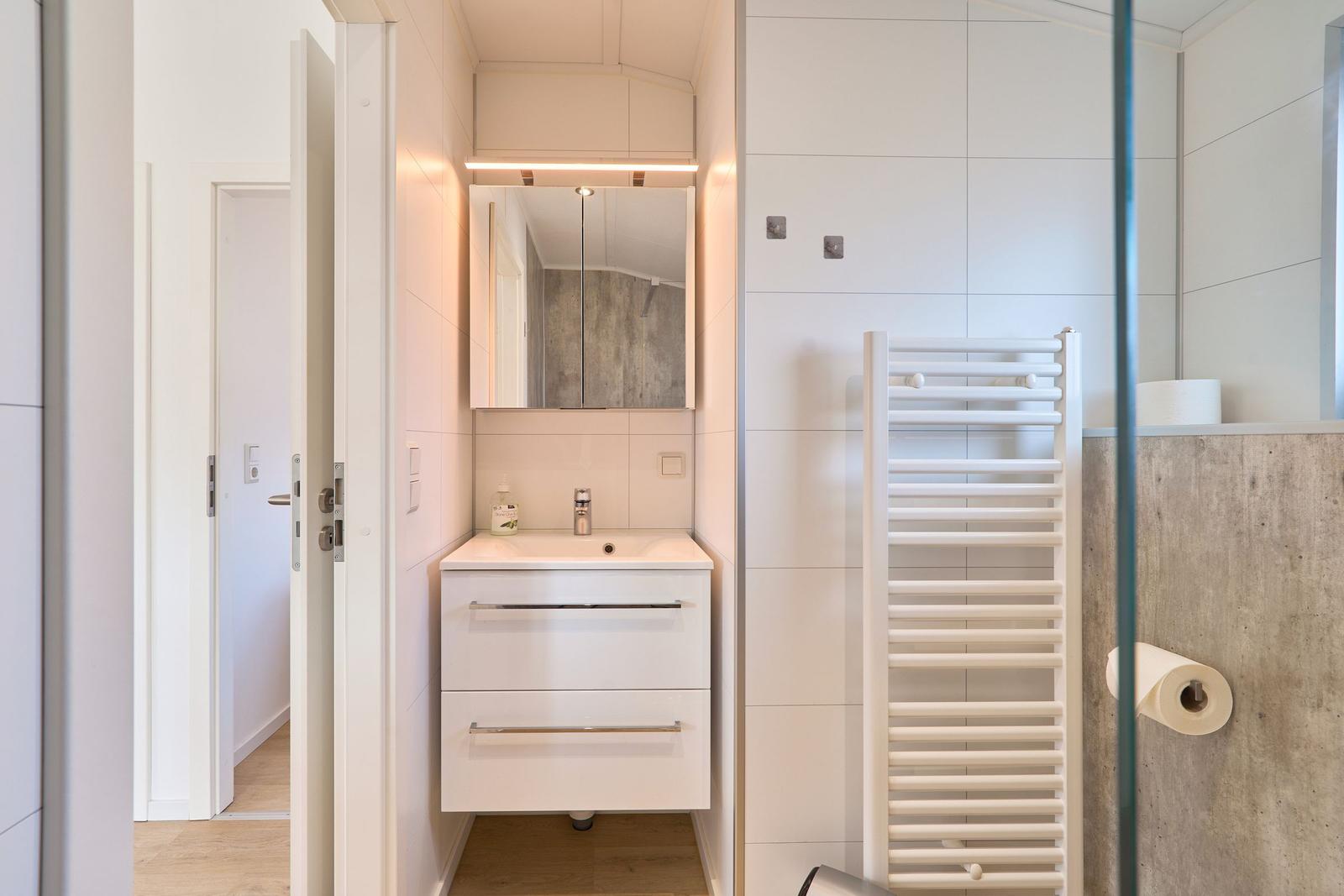 Badezimmer mit Waschbecken, Spiegel und Heizkörper