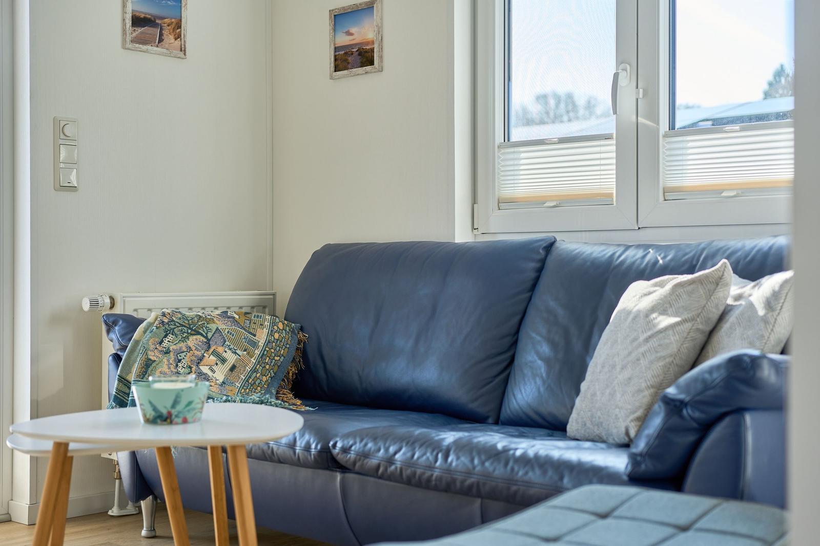 Ein Sofa mit Kissen und Tisch im Wohnzimmer mit Fenster und Wandbildern.