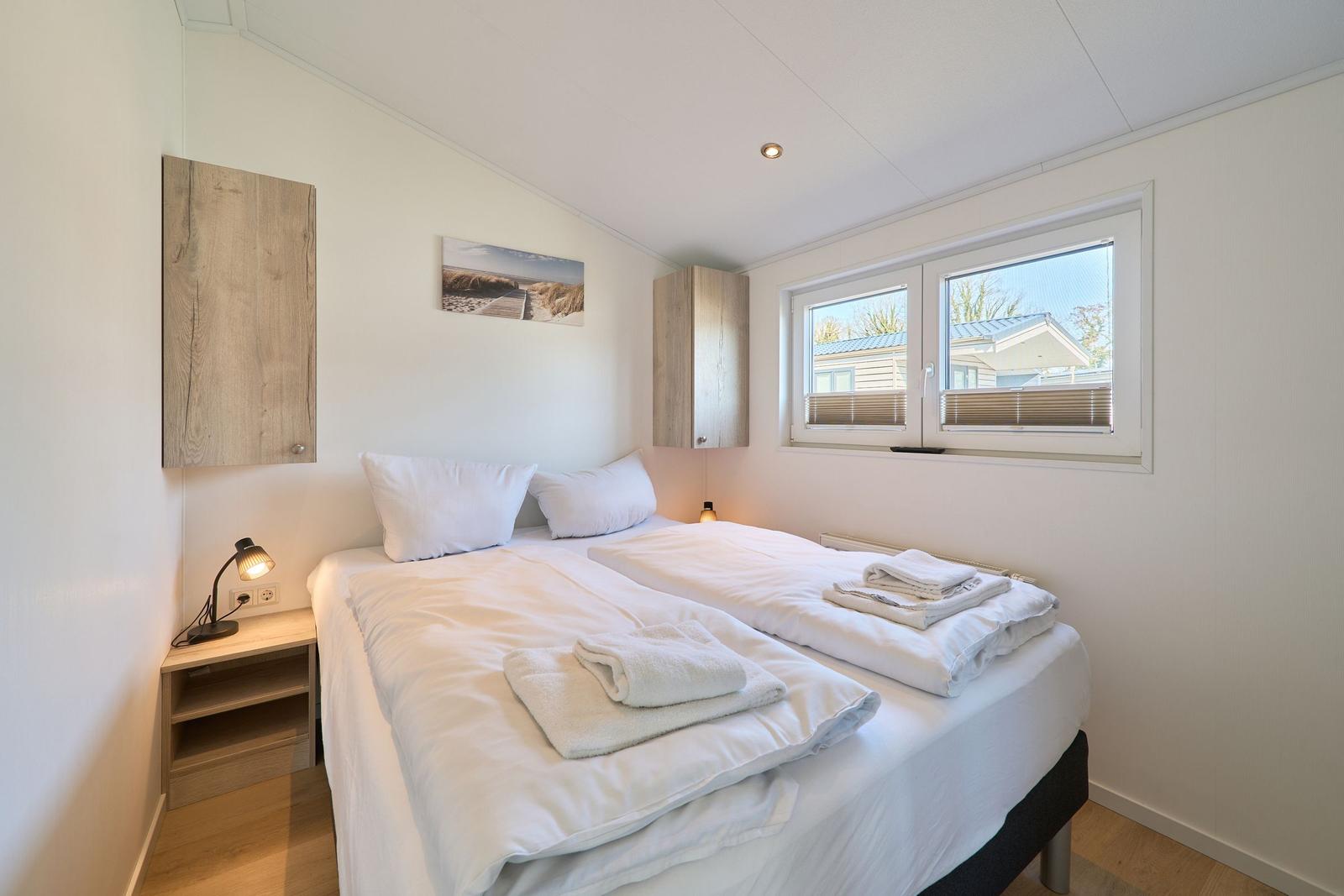 Ein Schlafzimmer mit Doppelbett, Fenster und Nachttisch.