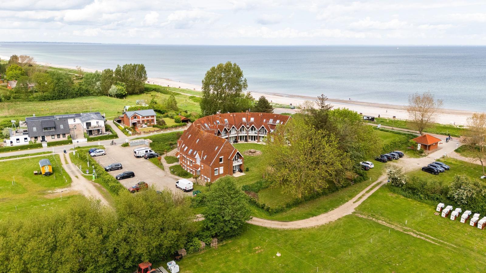 Haus mit rotem Dach, Parkplatz und Strand im Hintergrund.