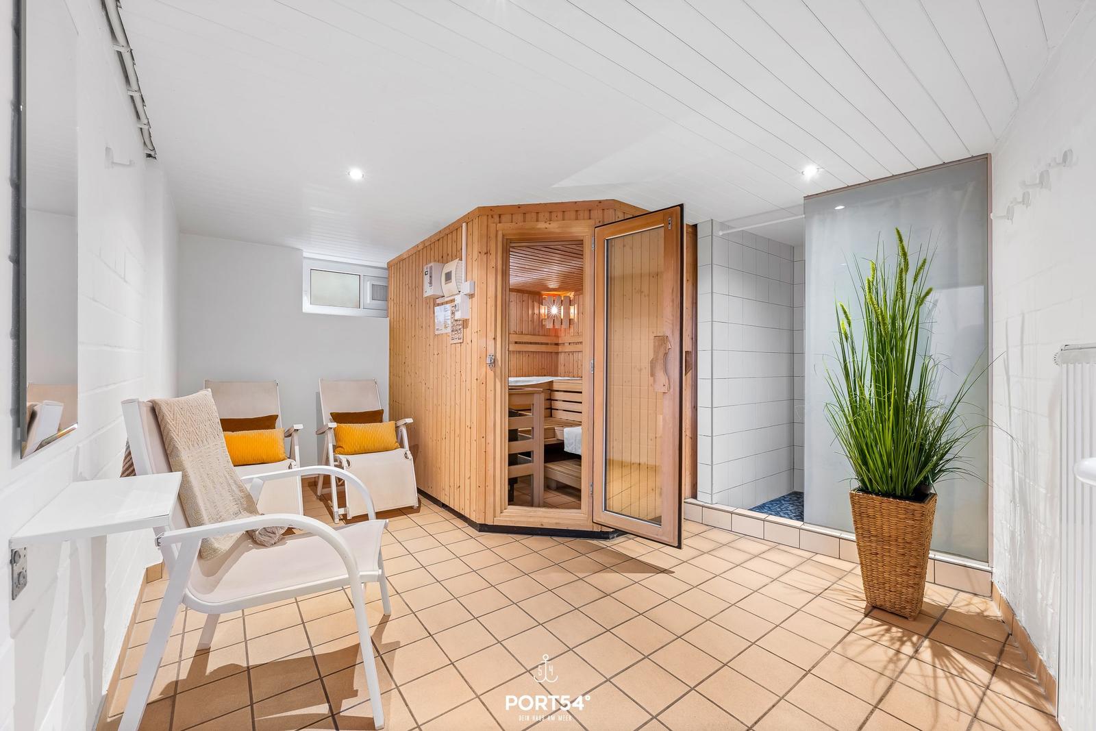 Sauna mit Holzbank, Sitzgelegenheiten und Dusche im Innenbereich.