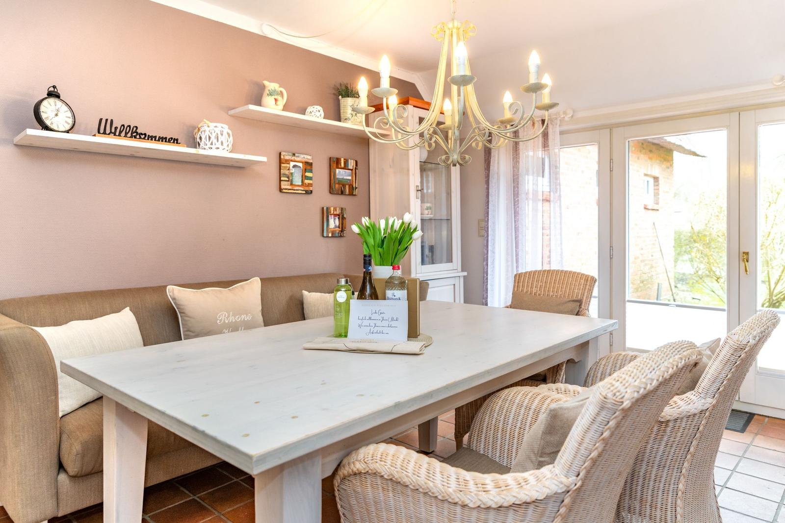 Esszimmer mit Esstisch, Stühlen und Sofa an der Wand. Hängende Regale und Kronleuchter.