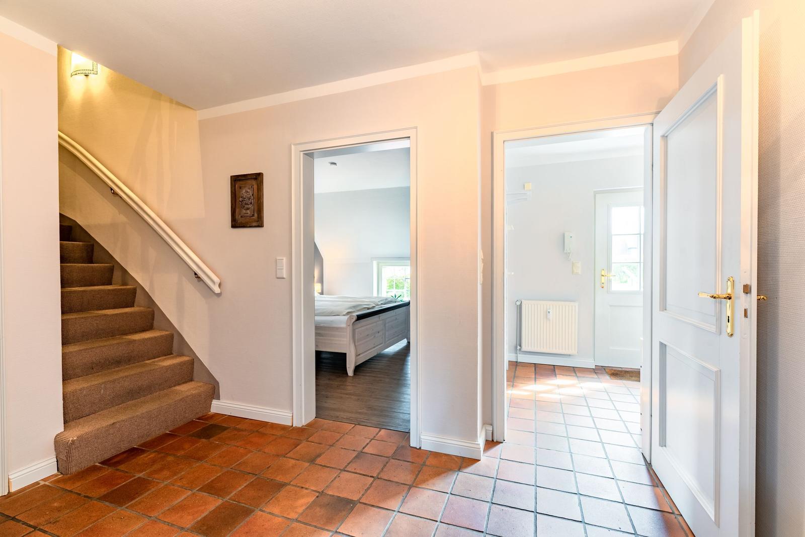 Hausflur mit Treppenaufgang, Schlafzimmer und Flur mit Heizkörper.