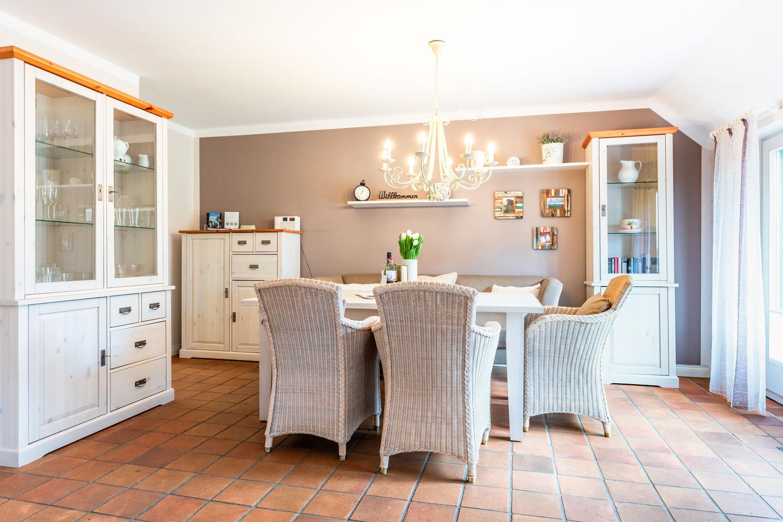 Esszimmer mit Esstisch, Stühlen und Schränken. Terrakottaboden und Deckenleuchte.