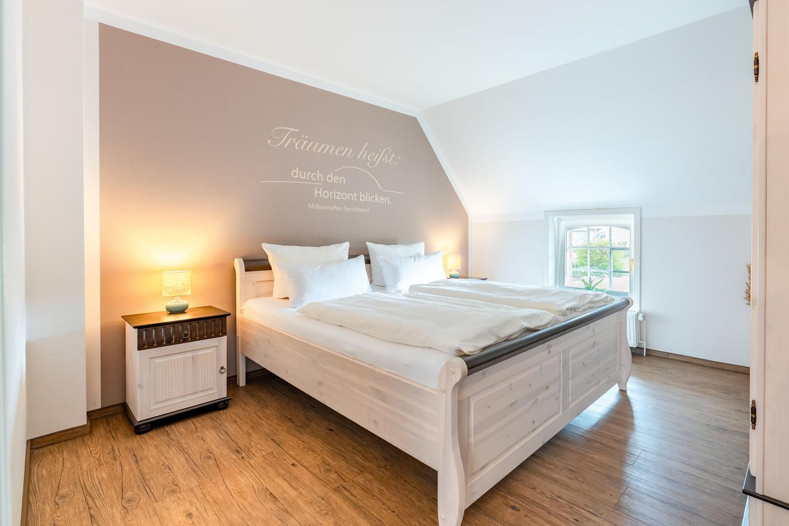 Schlafzimmer mit Doppelbett, Nachttisch und Wanddekoration.