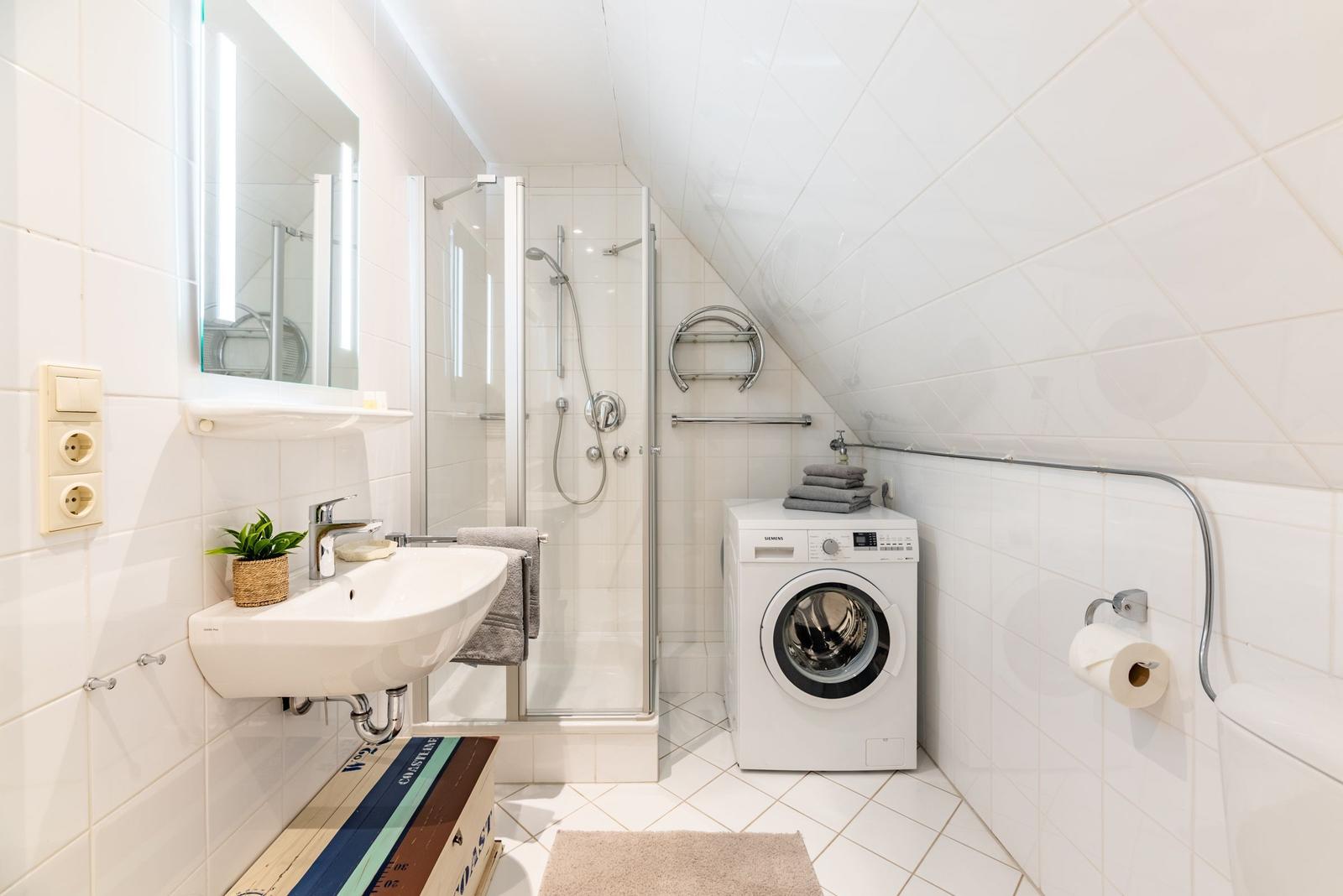 Badezimmer mit Dusche, Waschmaschine und Spiegel