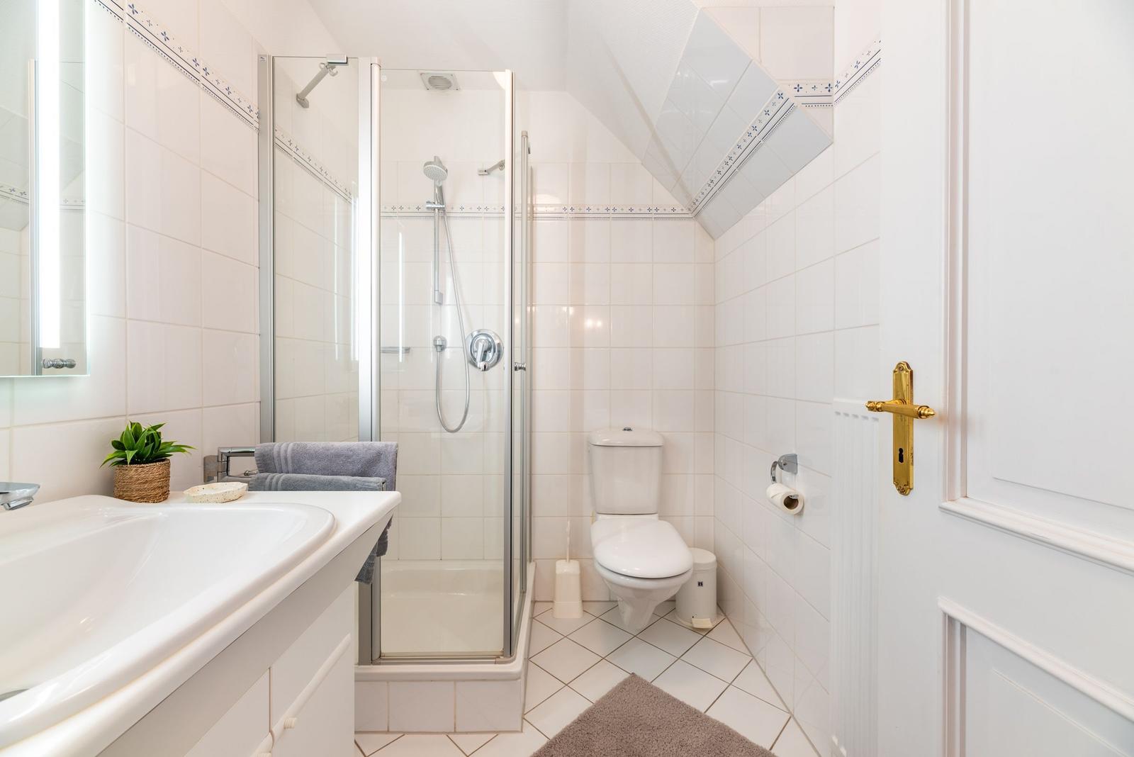 Badezimmer mit Dusche, Toilette und Waschbecken mit Spiegel.