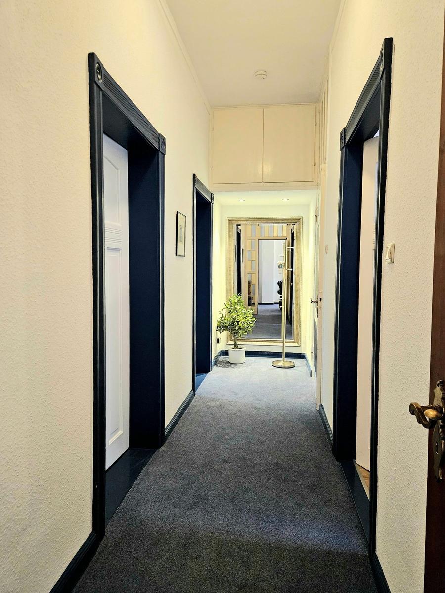 Hallway with carpeted floor, black door frames, and a plant in the center.