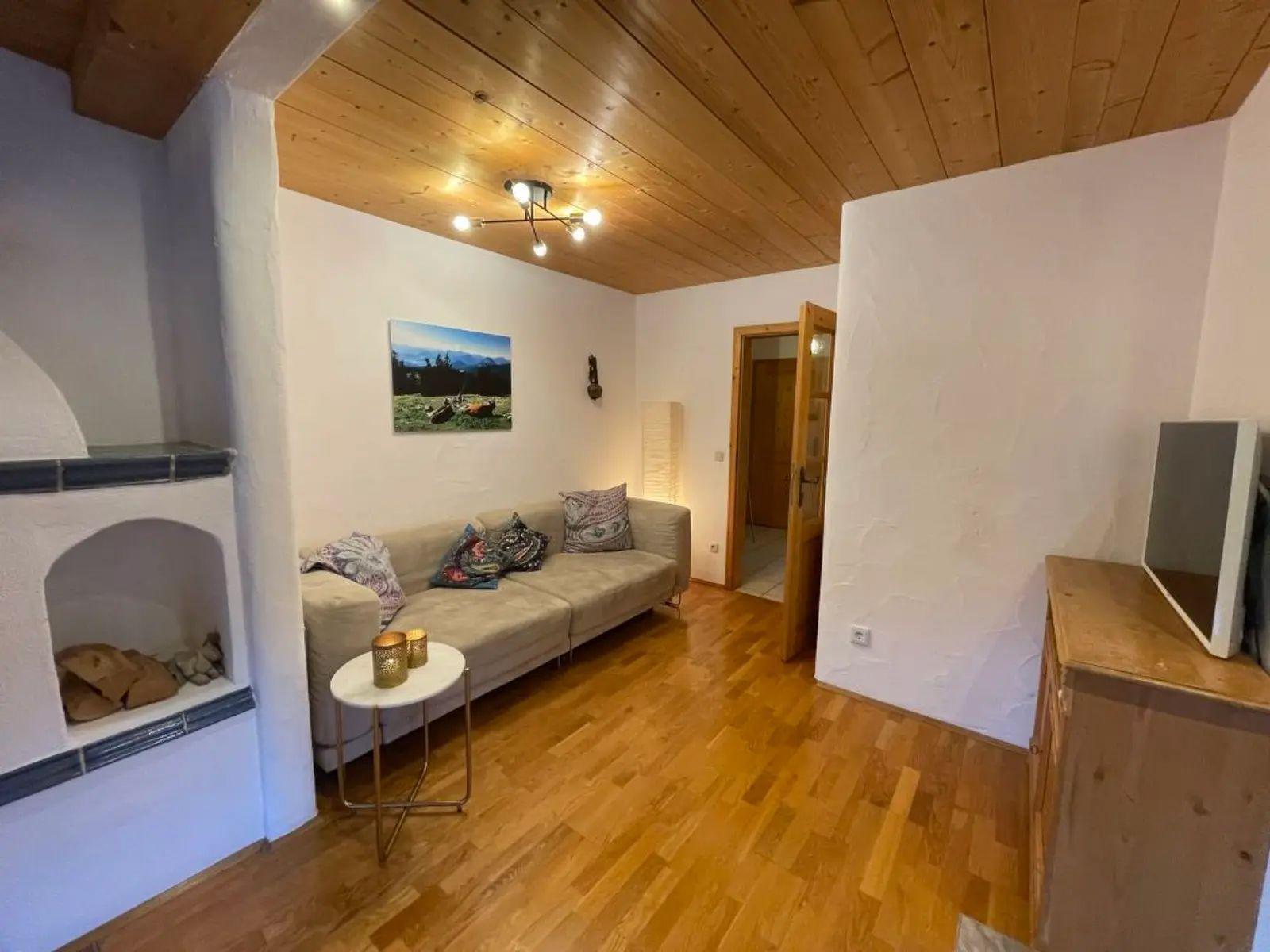 Wohnzimmer mit Holzboden, Sofa, Kamin und Fernseher.