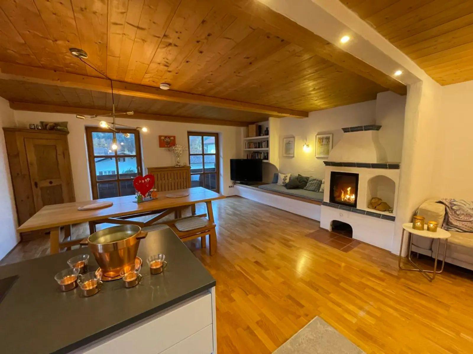 Wohnbereich mit Kamin, Essbereich und Holzboden. Einrichtung aus Holz und Metall.
