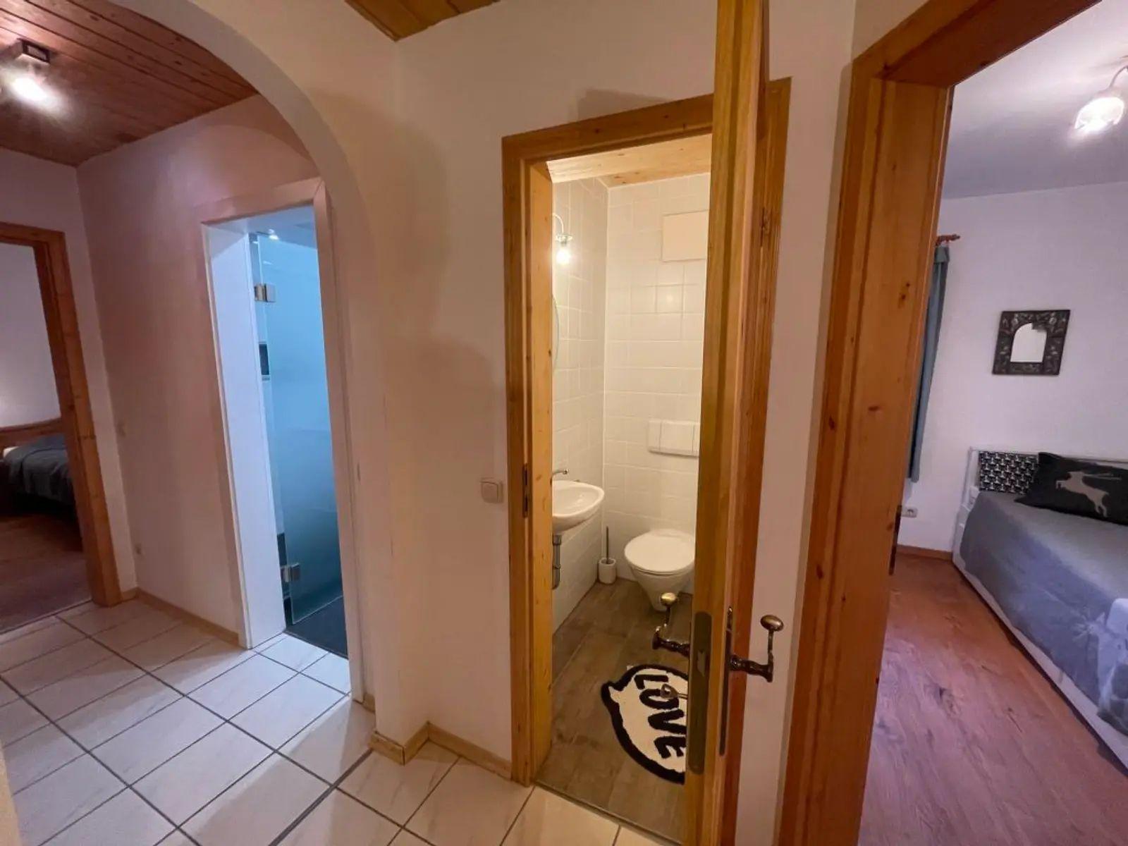 Flur mit Blick in Bad, Schlafzimmer und Dusche mit Glaswand.
