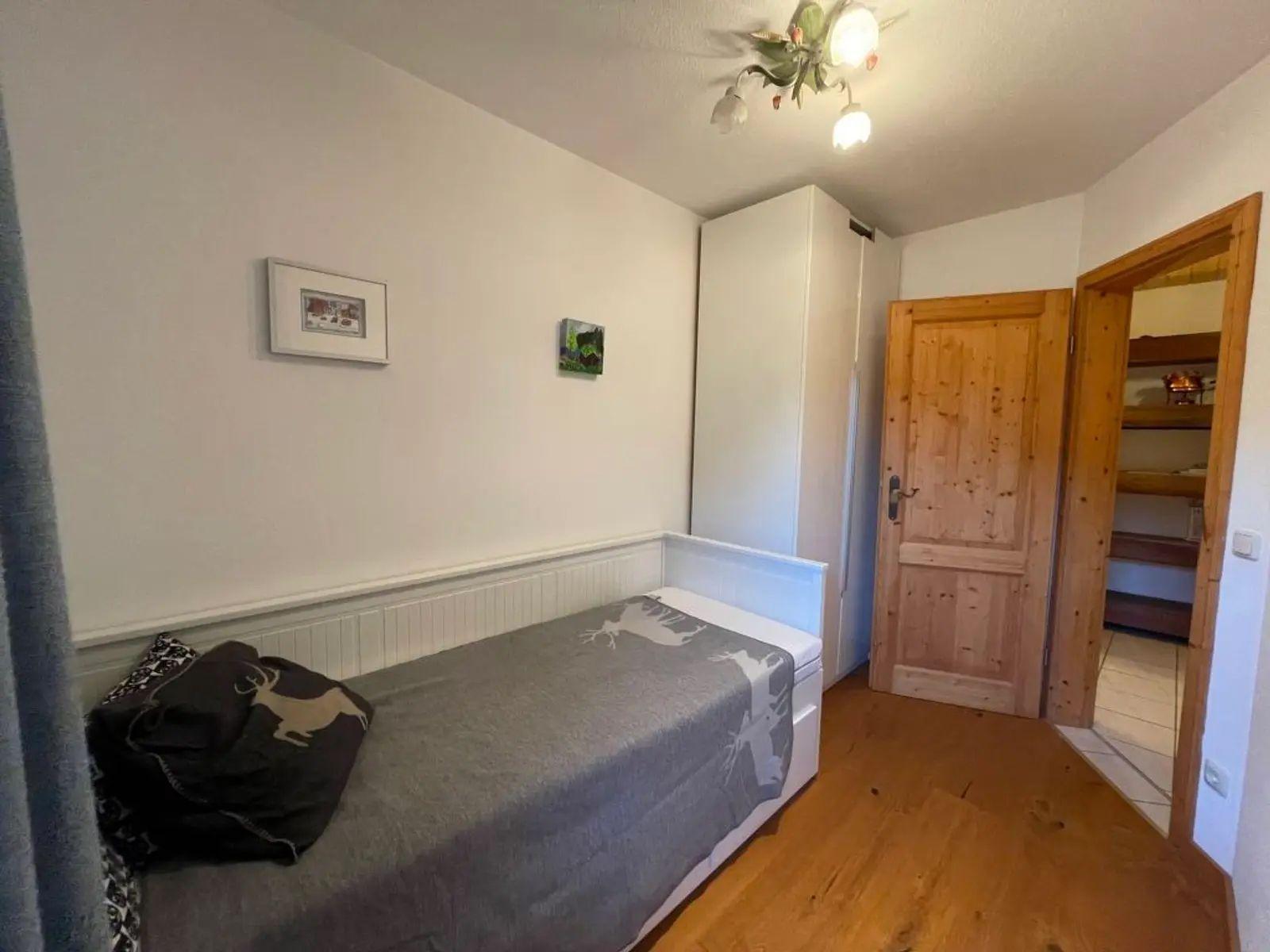 Schlafzimmer mit Bett, Kleiderschrank und Holztür. Holzfußboden und Wandbilder.