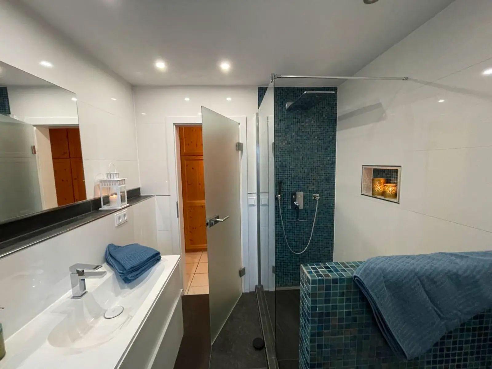 Badezimmer mit Dusche, Waschbecken und Badewanne mit Mosaikfliesen.