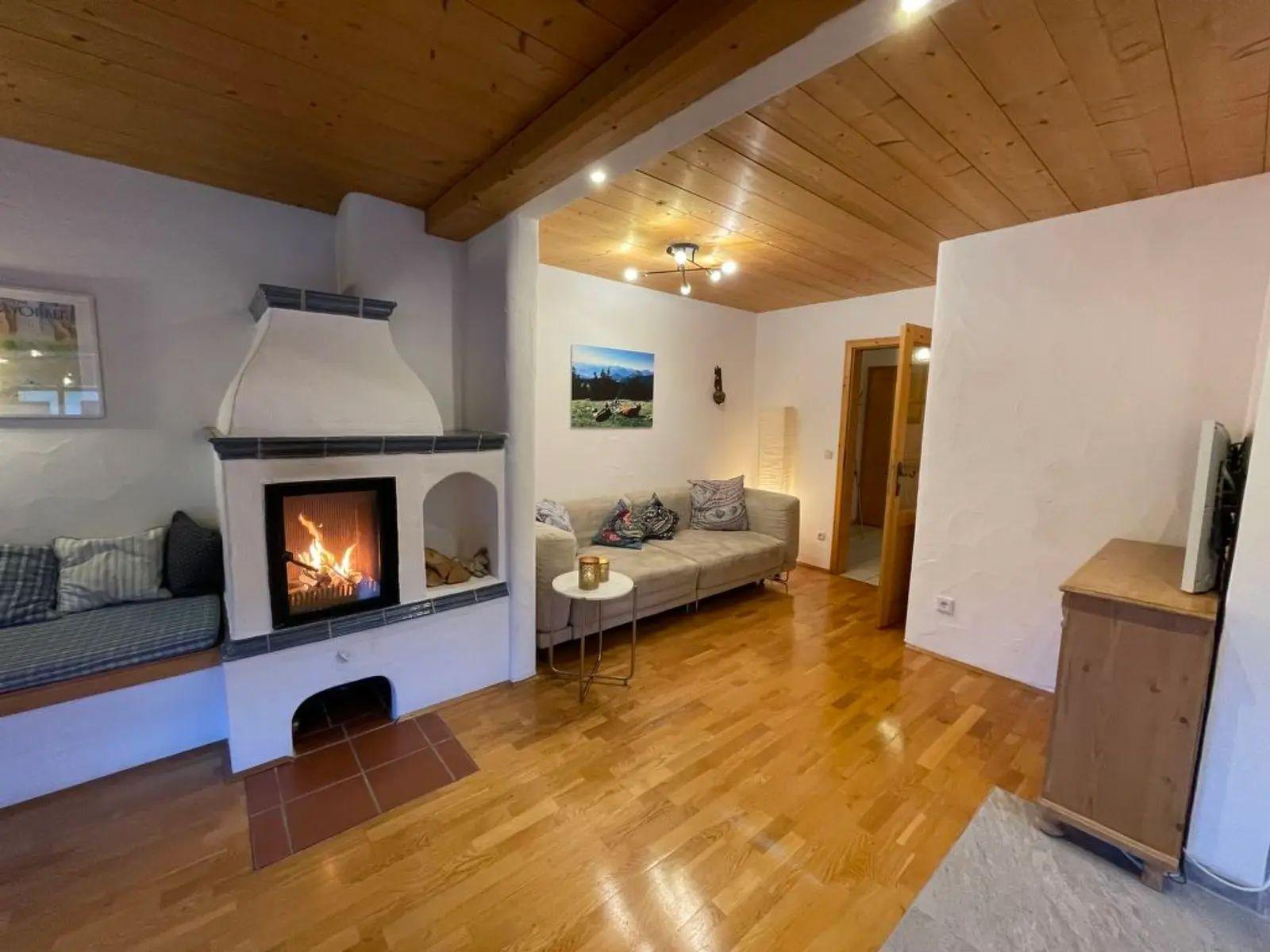 Wohnzimmer mit Kamin, Sofa und Holzboden. Decke aus Holz, Wandbild und Fernseher.