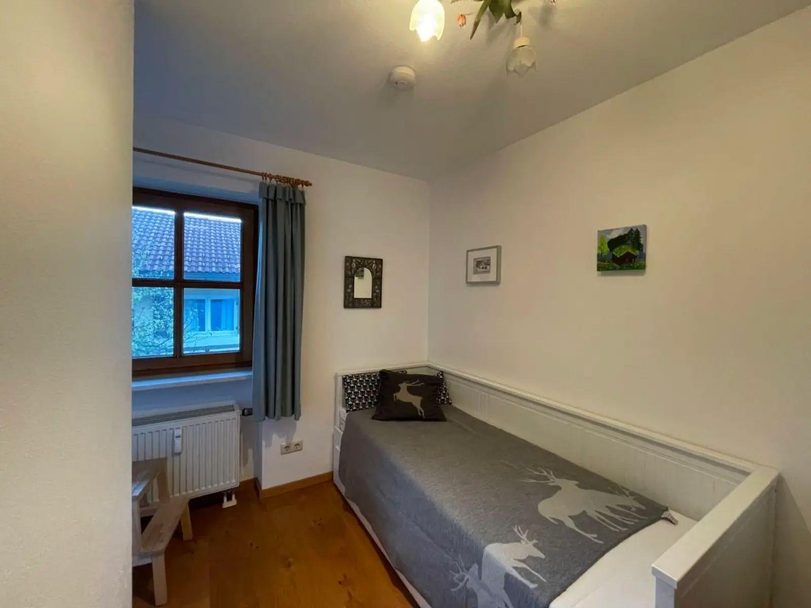 Schlafzimmer mit Bett, Fenster und Wandbildern.