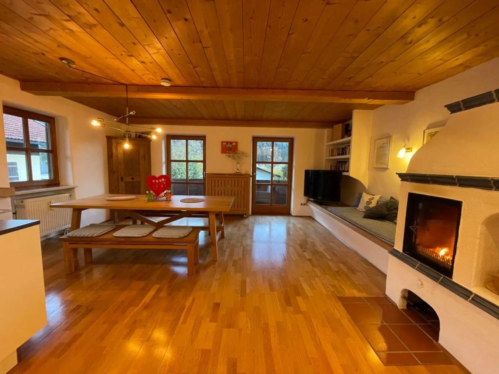 Großes Wohnzimmer mit Holzdecke, Kamin und Essbereich mit Tisch und Bänken.