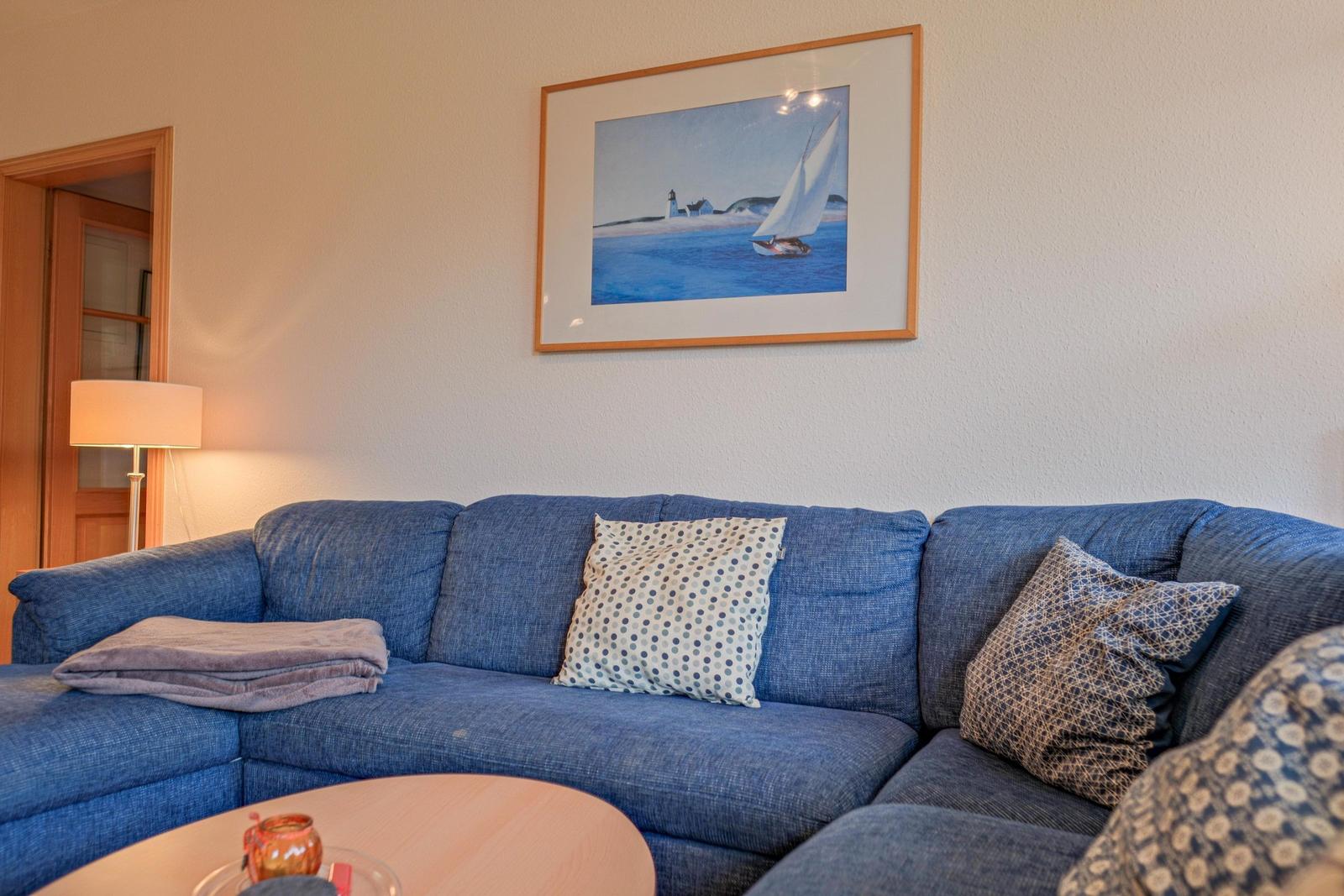 Blauer Sofa mit Kissen und Bild an der Wand