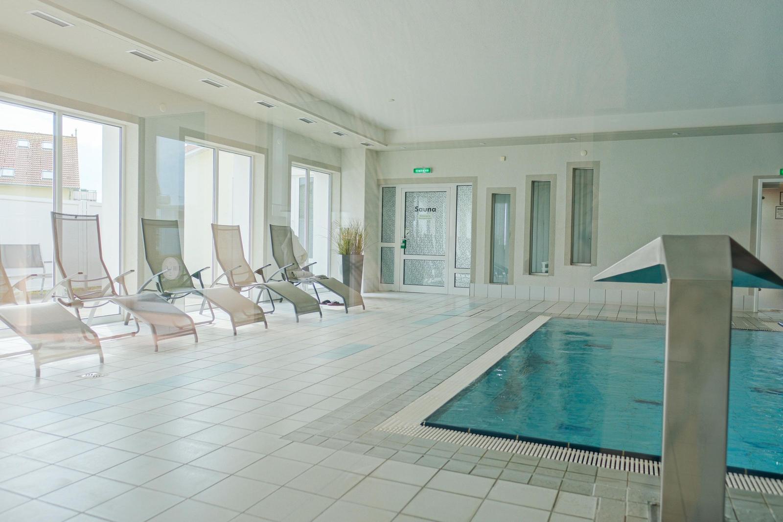 Innenpool mit Liegestühlen und Sauna-Tür