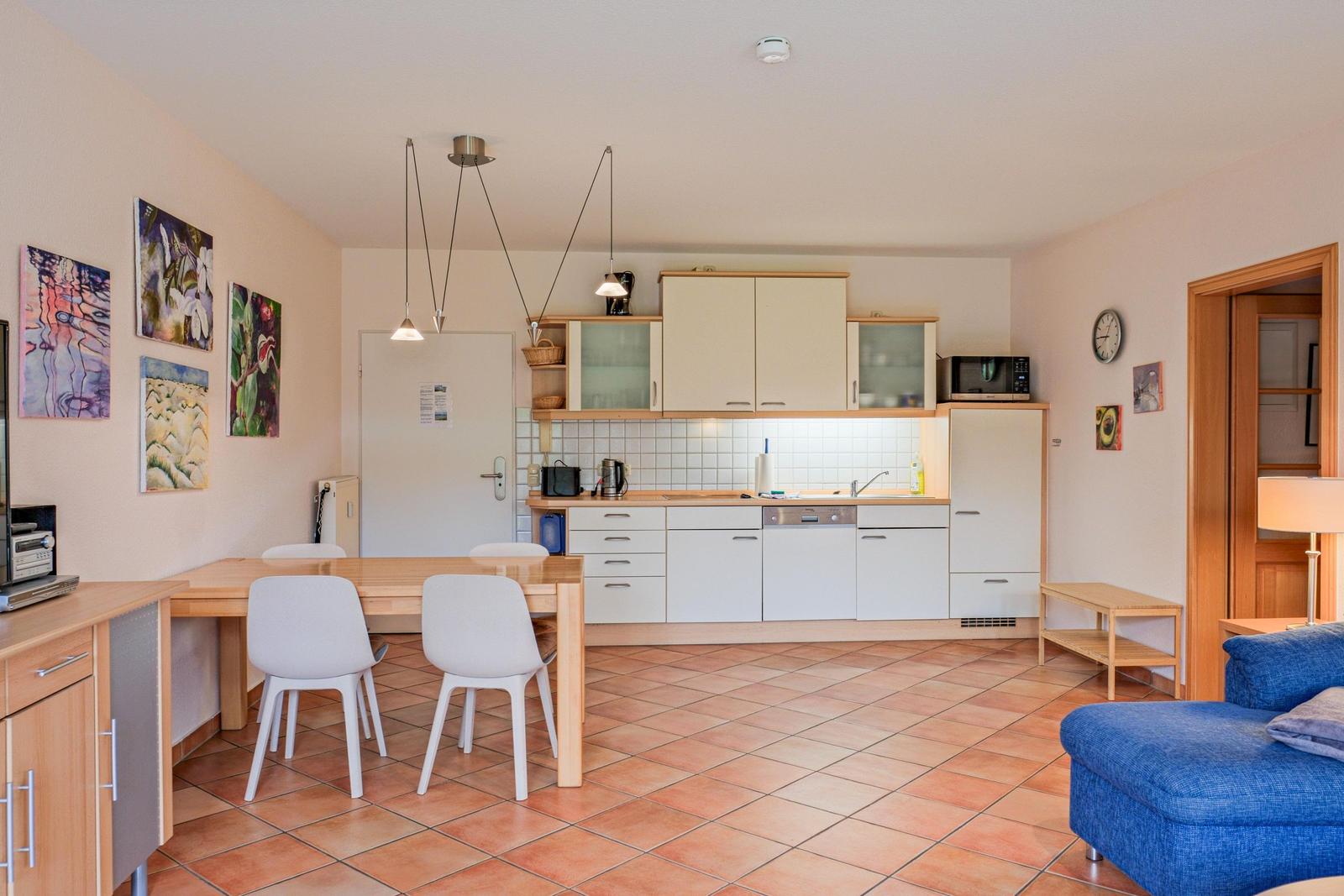 Küche mit Essbereich und blauer Couch im Wohnzimmer