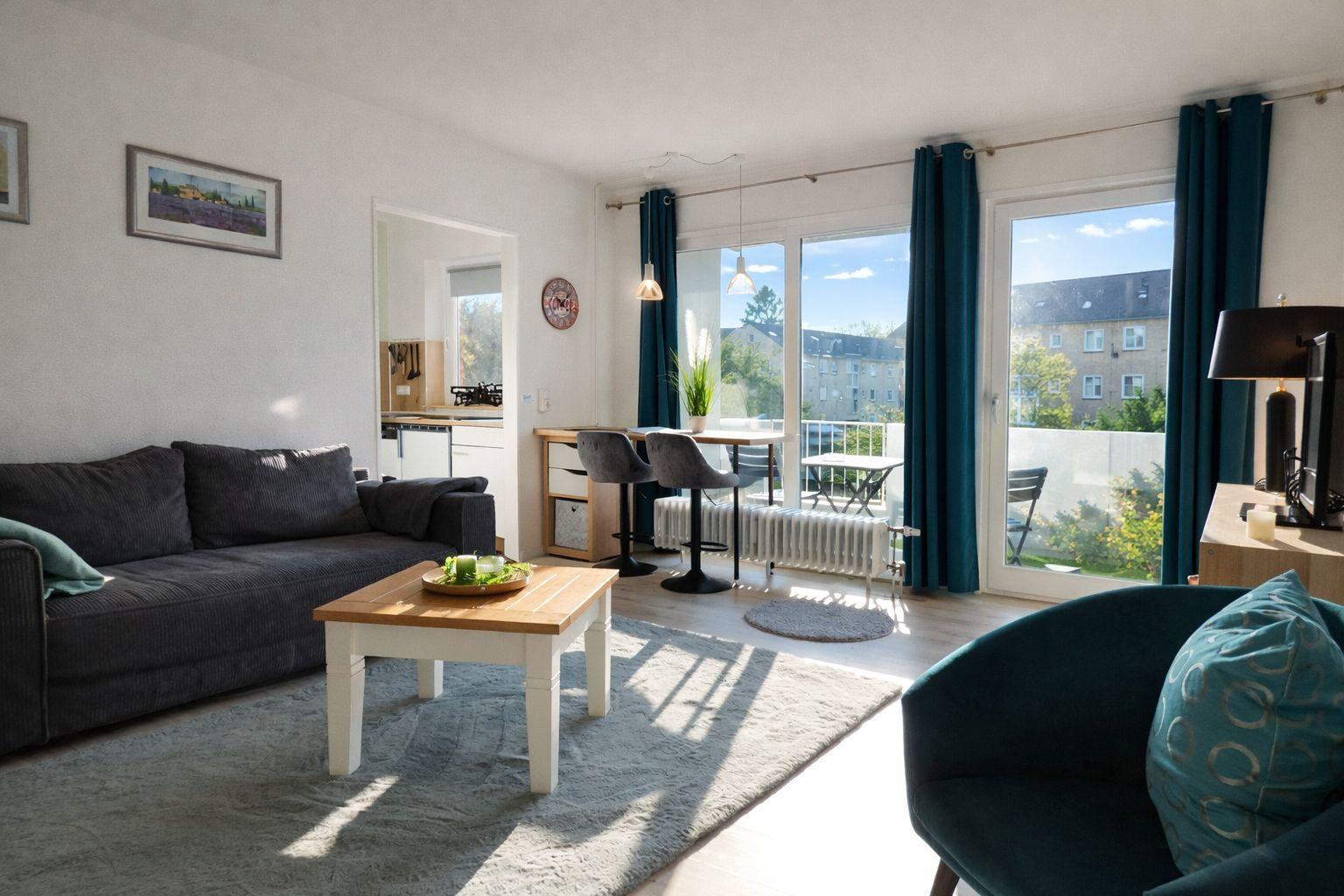 Wohnung mit Sofa, Couchtisch und Blick auf Balkon mit Gartenansicht.