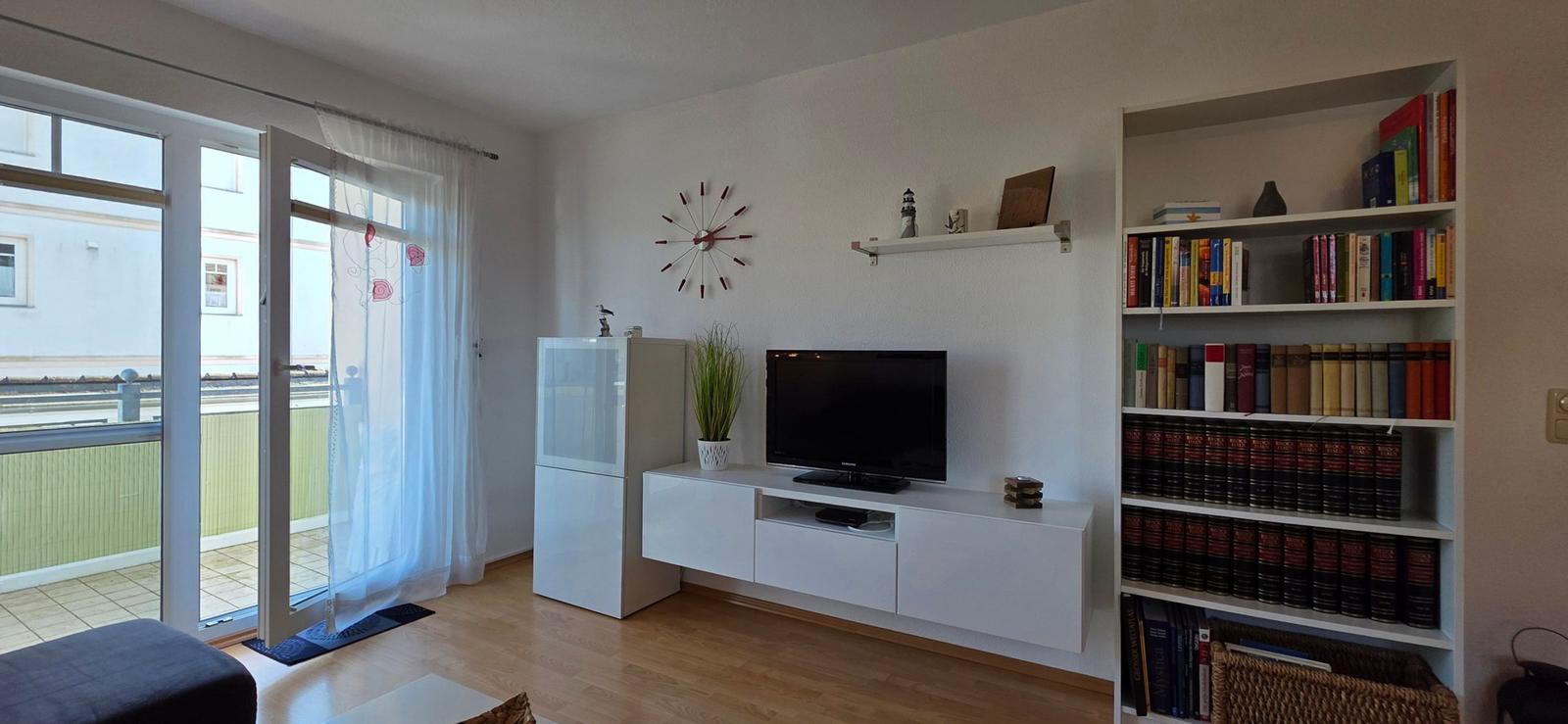 Wohnzimmer mit TV, Bücherregal und Terrassentür.