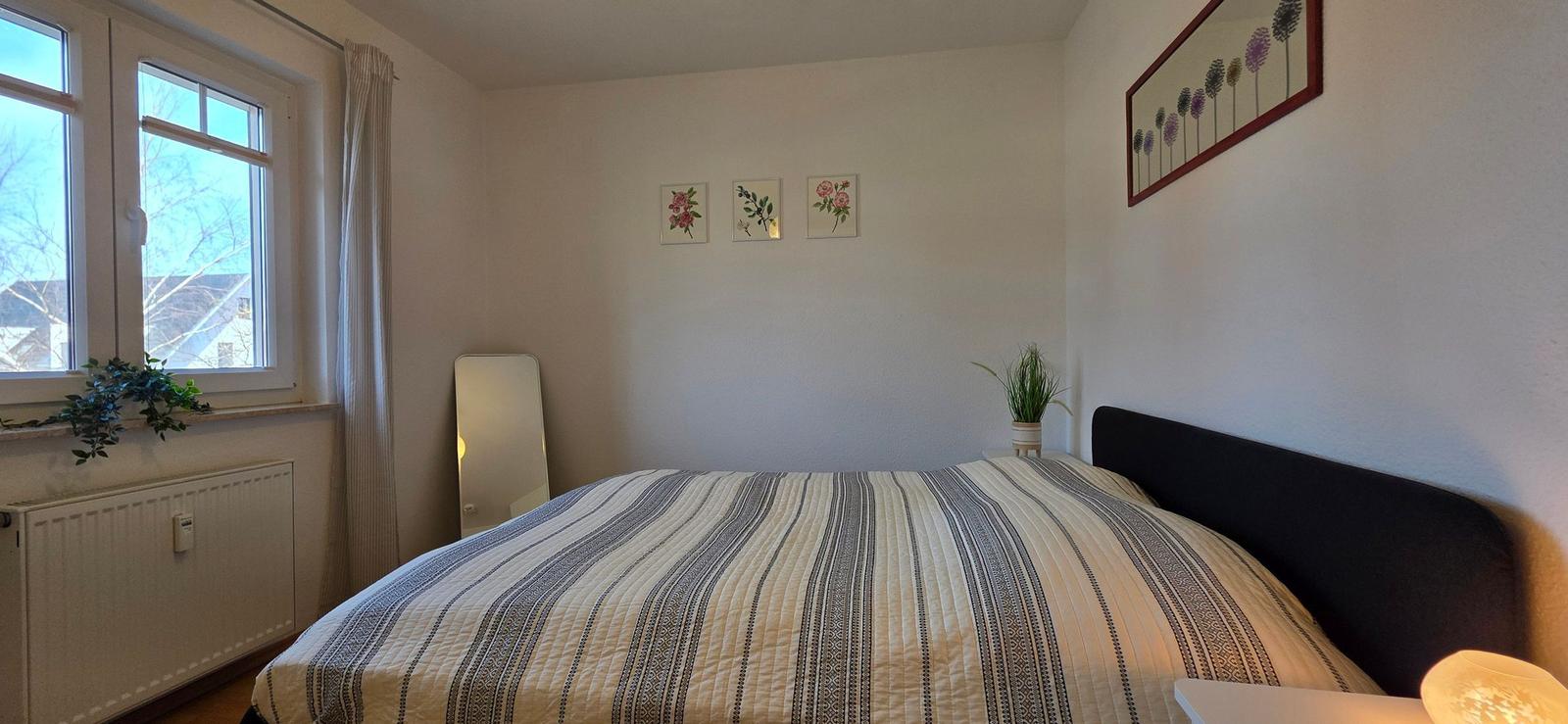 Schlafzimmer mit Bett, Fenster und Wanddekoration.