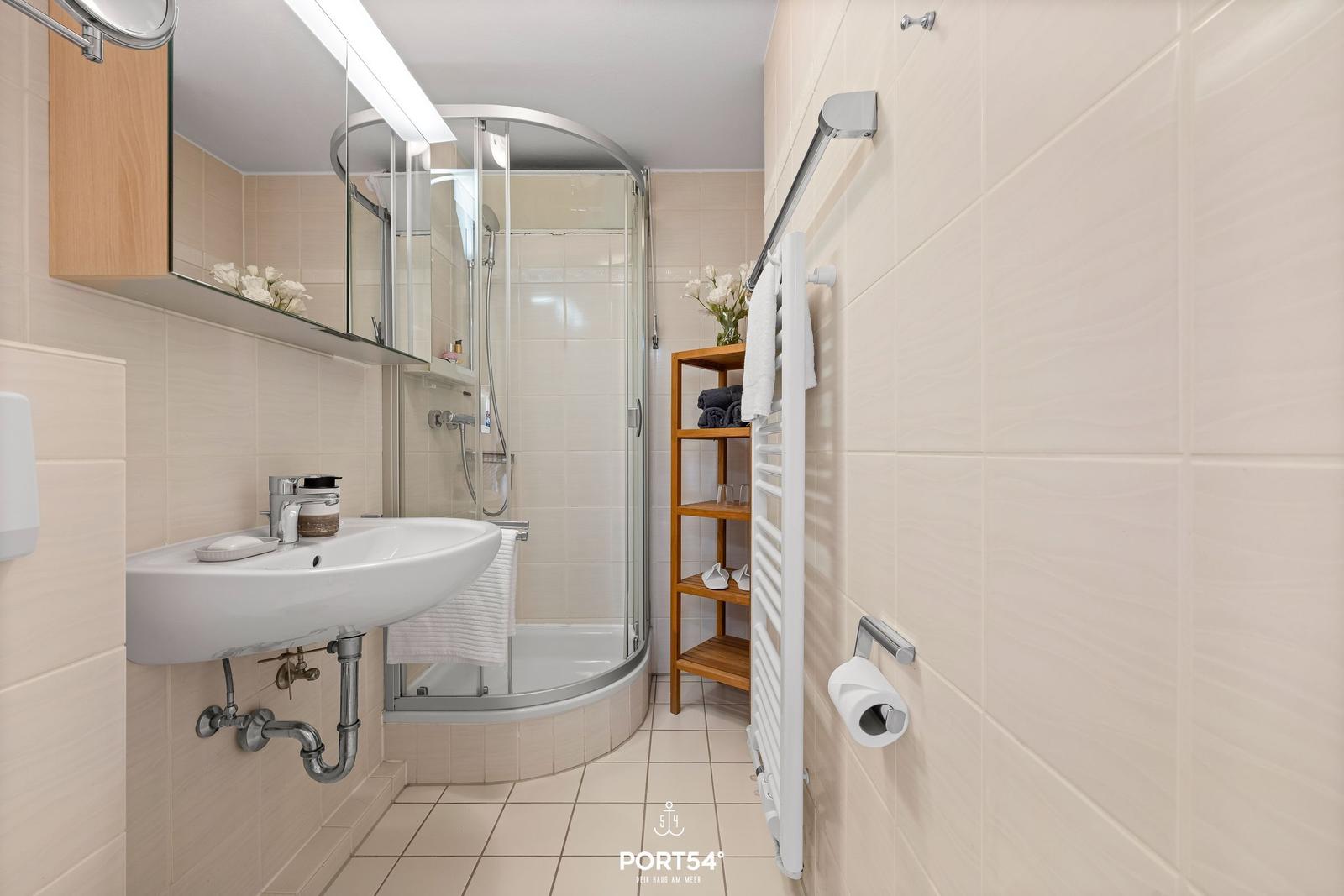 Badezimmer mit Dusche, Waschbecken und Handtuchhalter.
