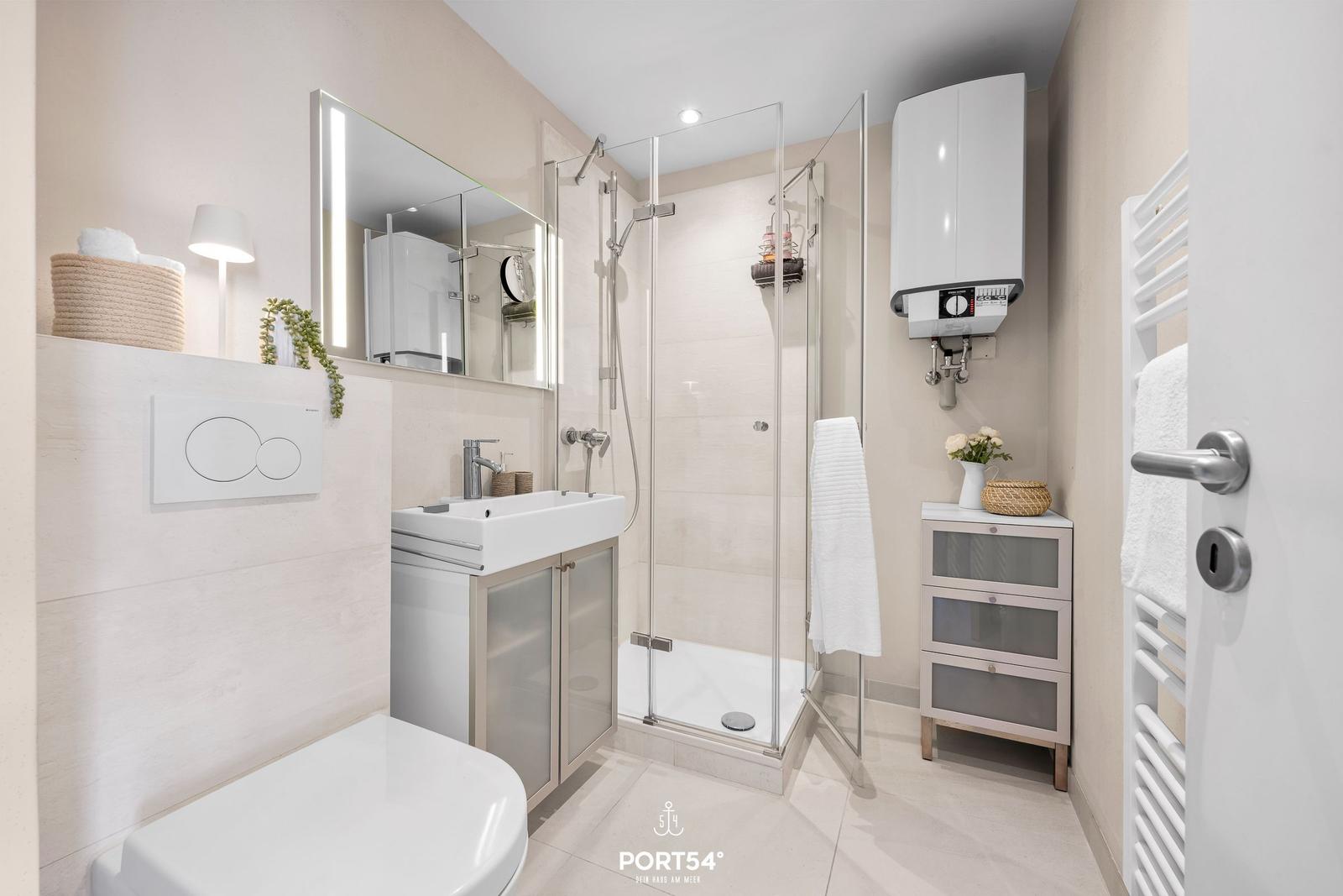 Badezimmer mit Dusche, Waschbecken und Toilette. Moderne Einrichtung und hell.