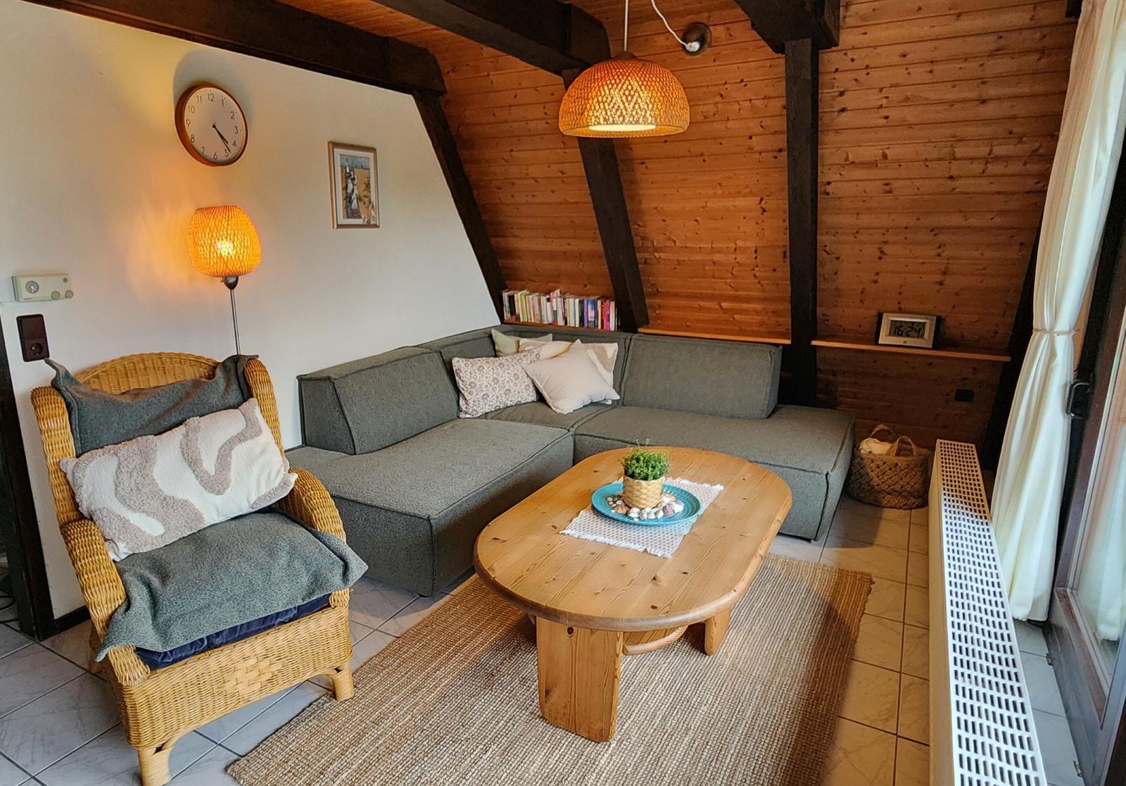 Living room with sofa, armchair, wooden table, and wood wall