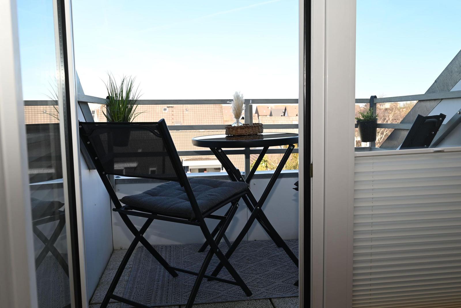 Terrasse mit Stuhl und Tisch, Pflanzen und Blick auf Dächer.