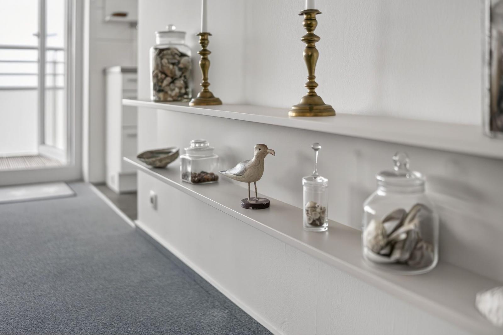 Wall shelf with glass jars, candle holders, and bird decoration.