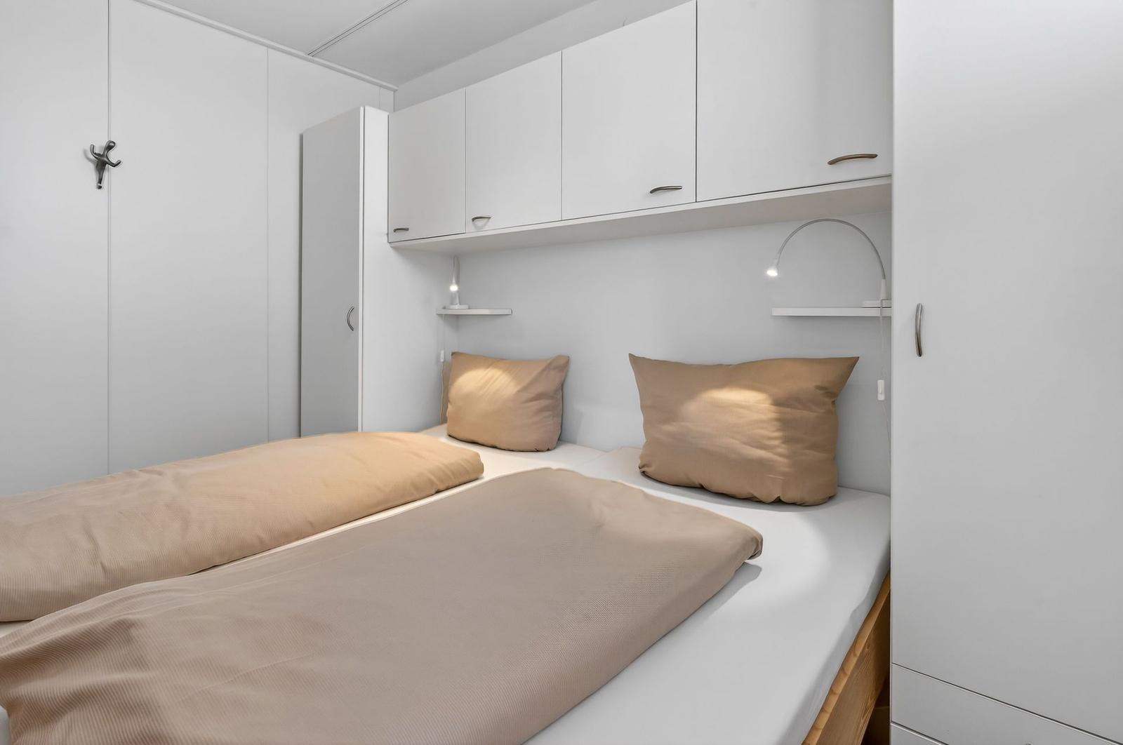 Bedroom with double bed, white cabinets, and bedside lamps.