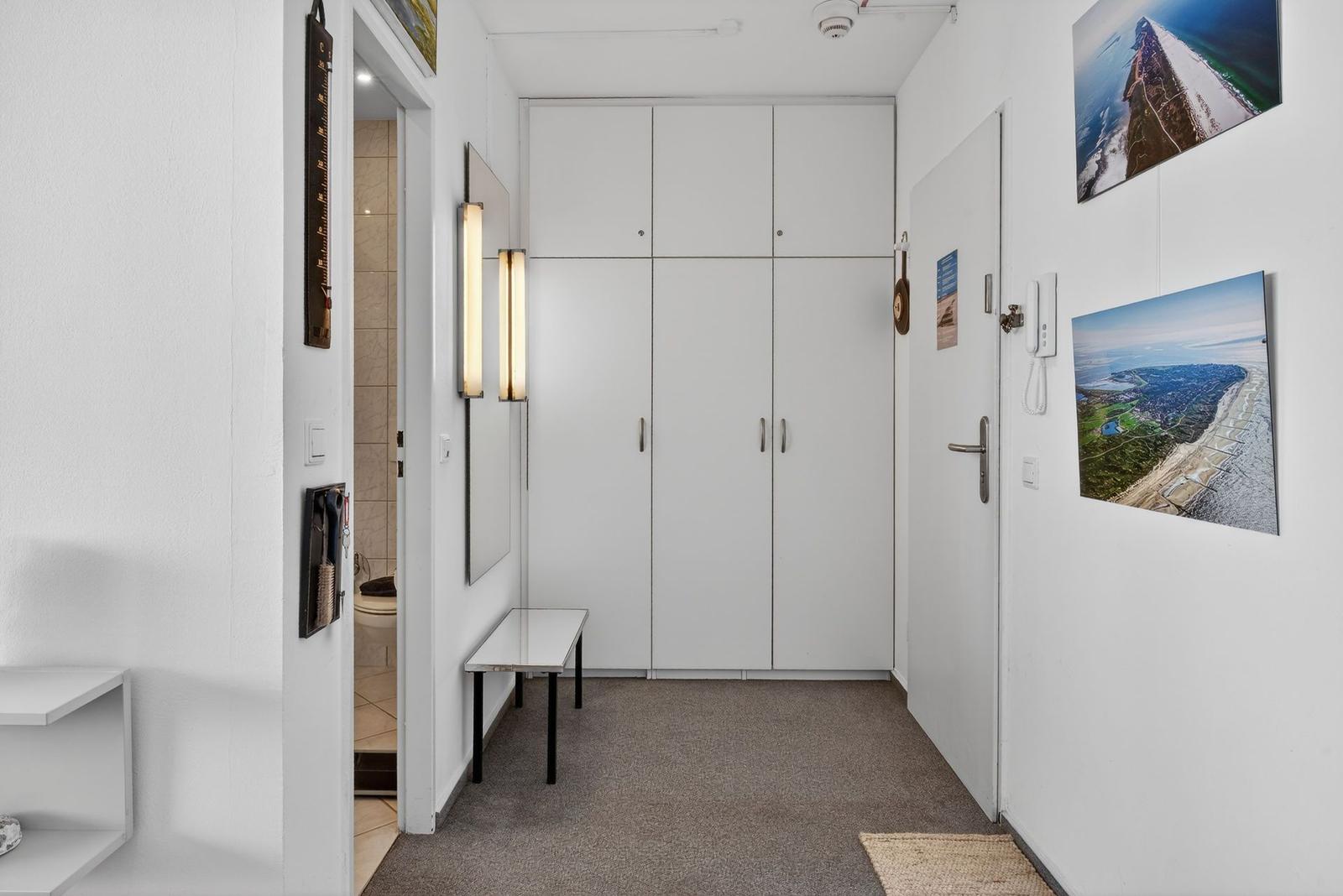 Hallway with shoe cabinet, bathroom, and wall pictures