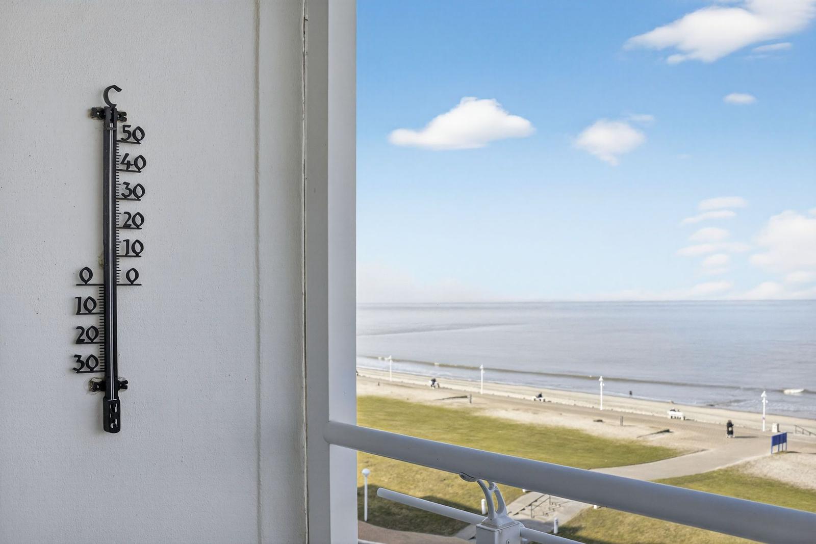 Outdoor view from balcony with thermometer and view of beach and sea.